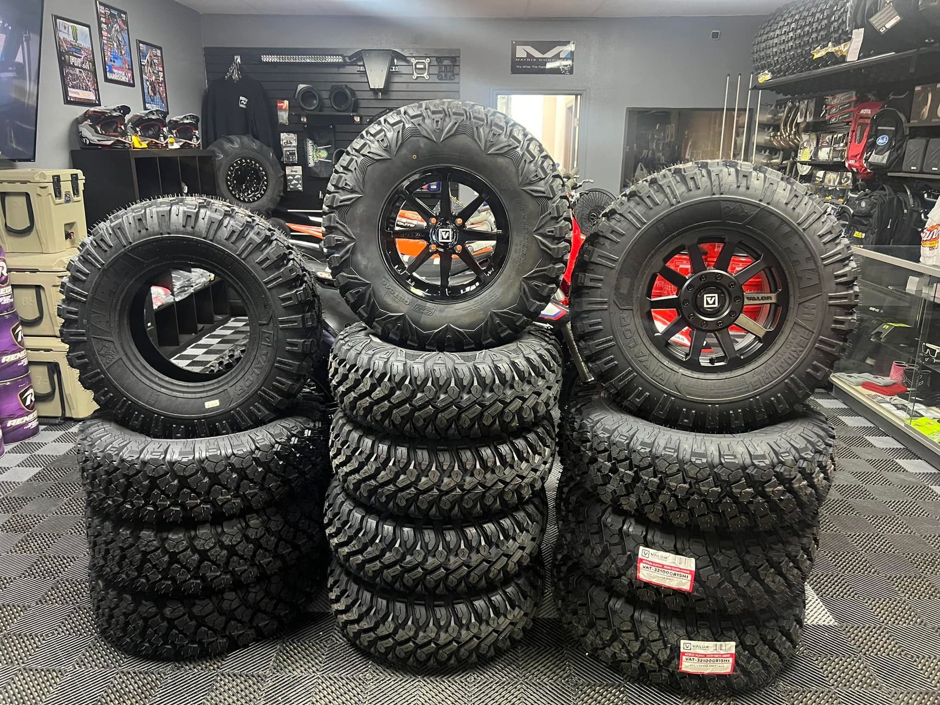 A bunch of tires and wheels are stacked on top of each other in a store.