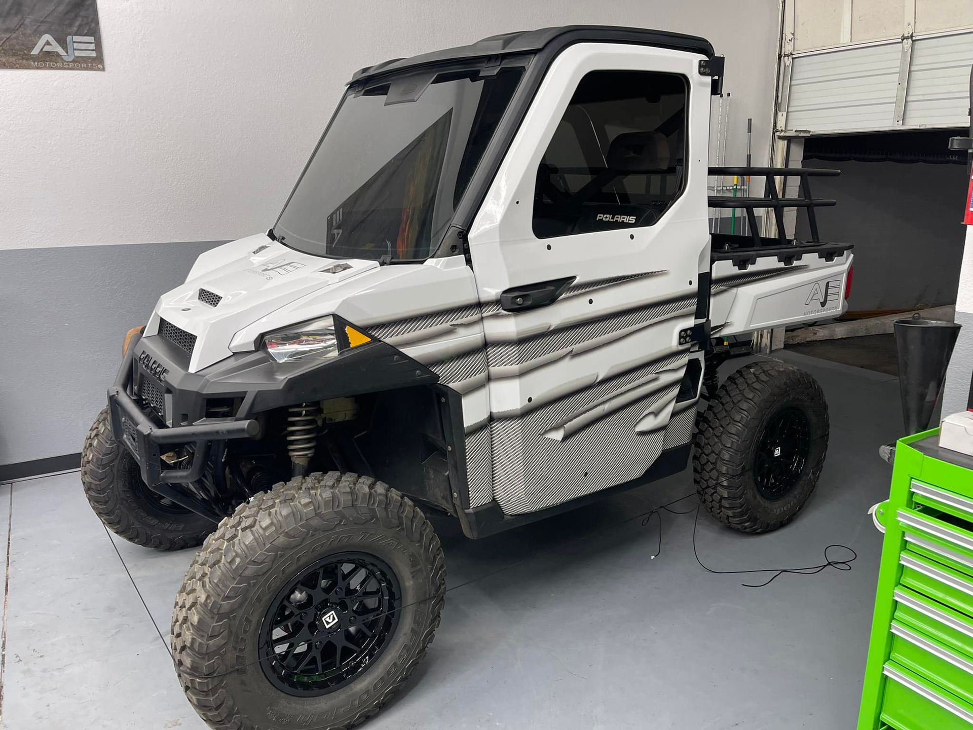 A white utility vehicle is parked in a garage next to a green toolbox.