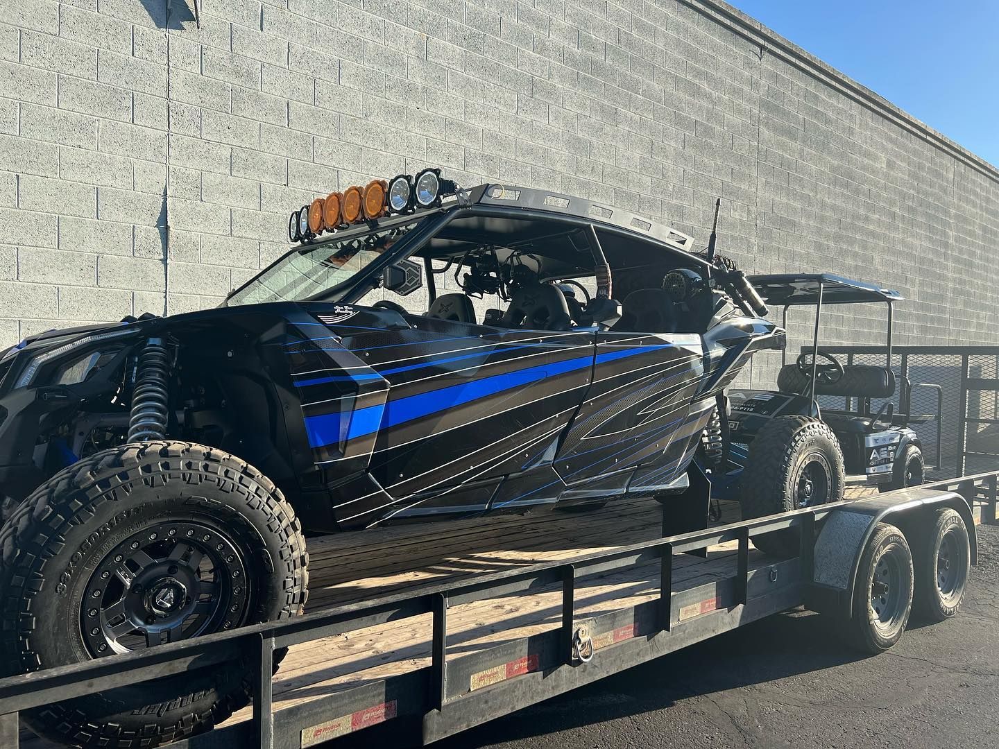 A blue and black buggy is being towed on a trailer.