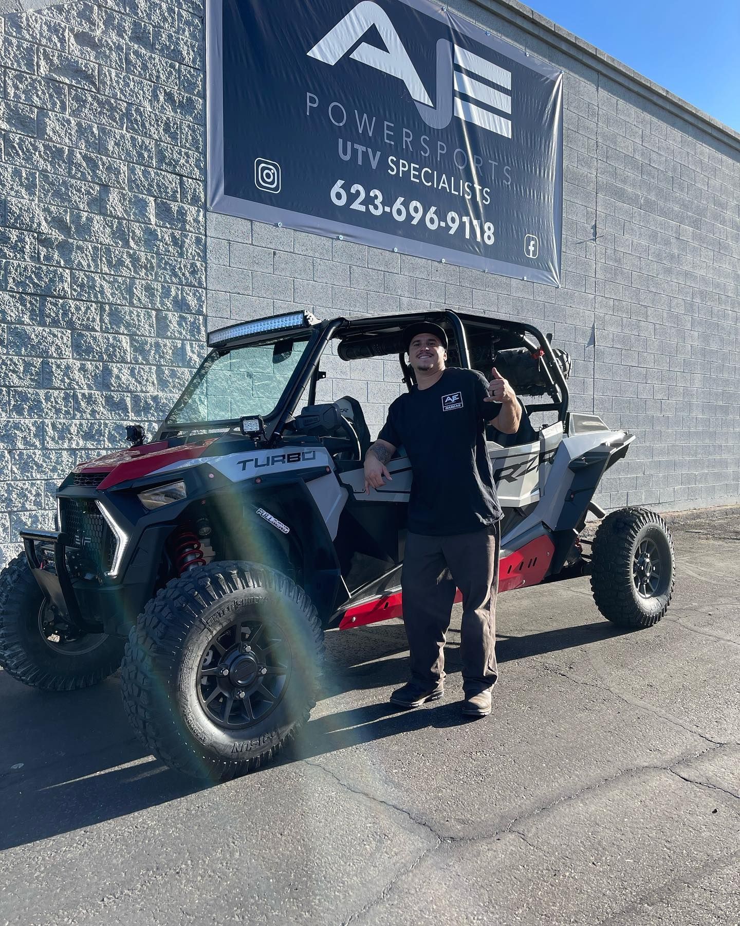 A man is standing in front of a polaris rzr 1000 atv.