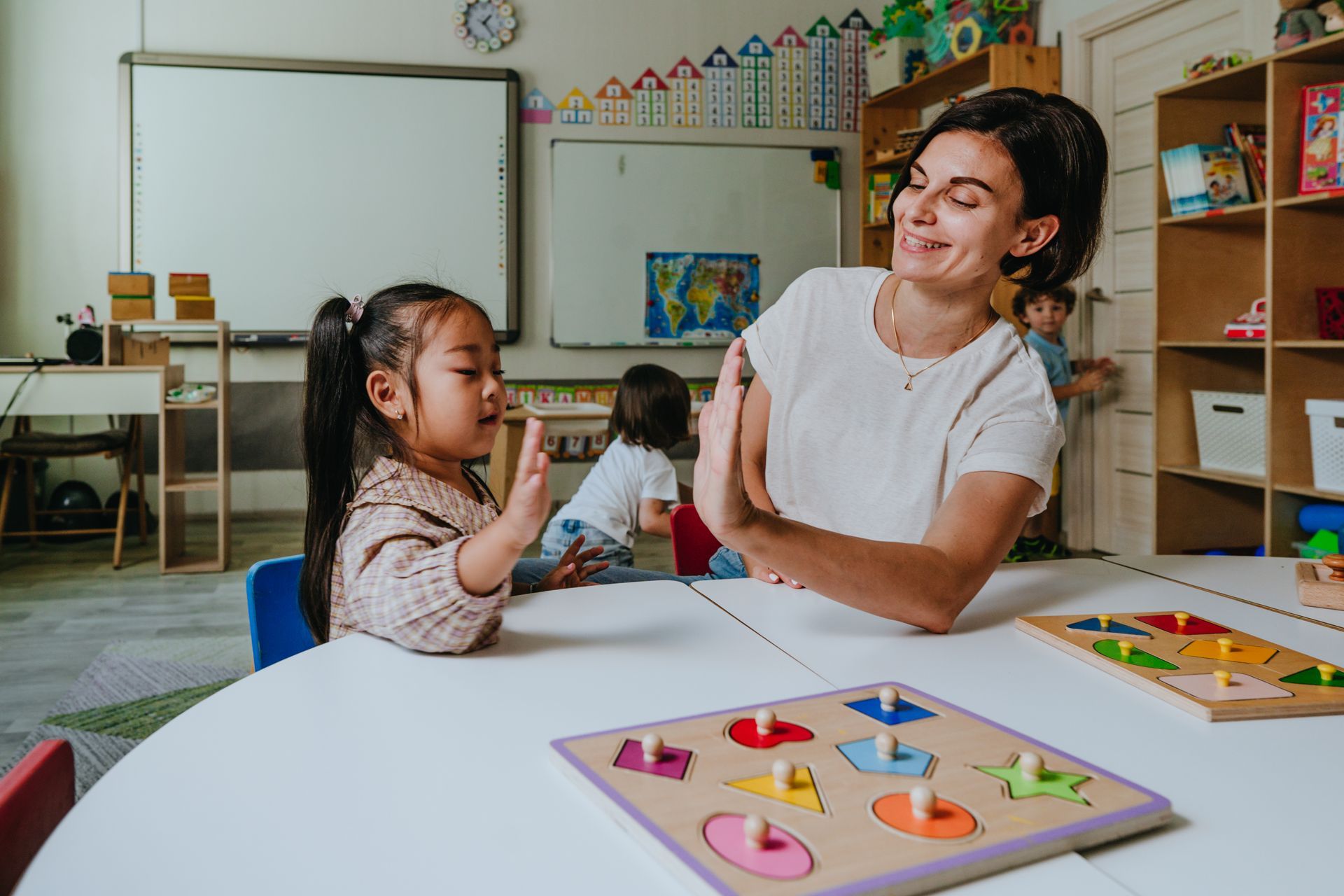 Girl and teacher playing with educational wooden toys in a kindergarten.
