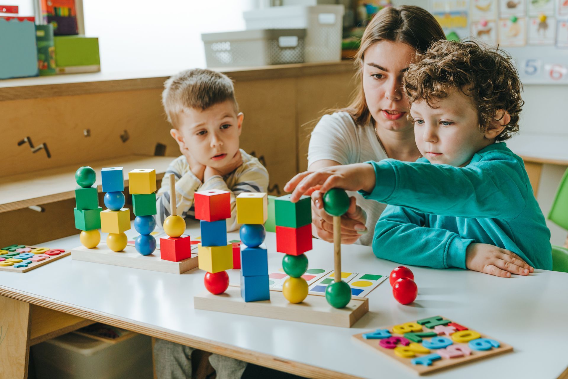 Female teacher helping little boy sort the cubes by color in a kindergarten