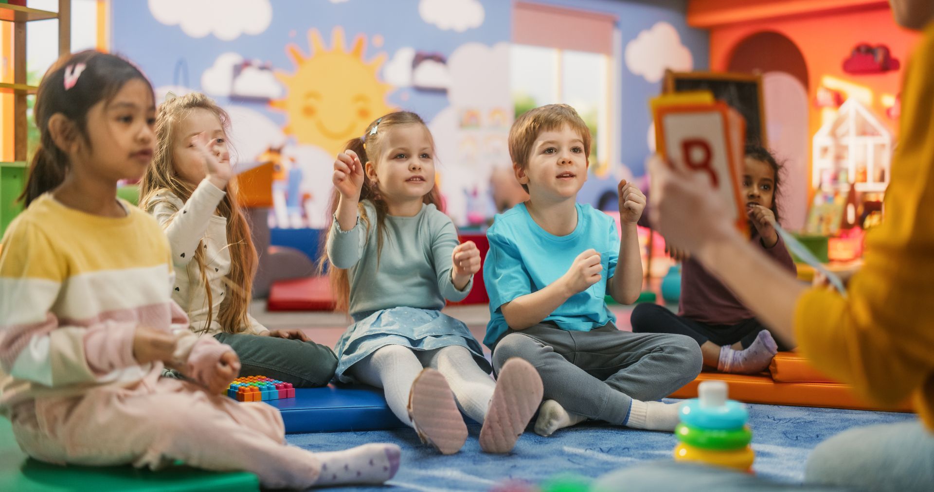 Cheerful preschool teacher playing and studying creatively with children.