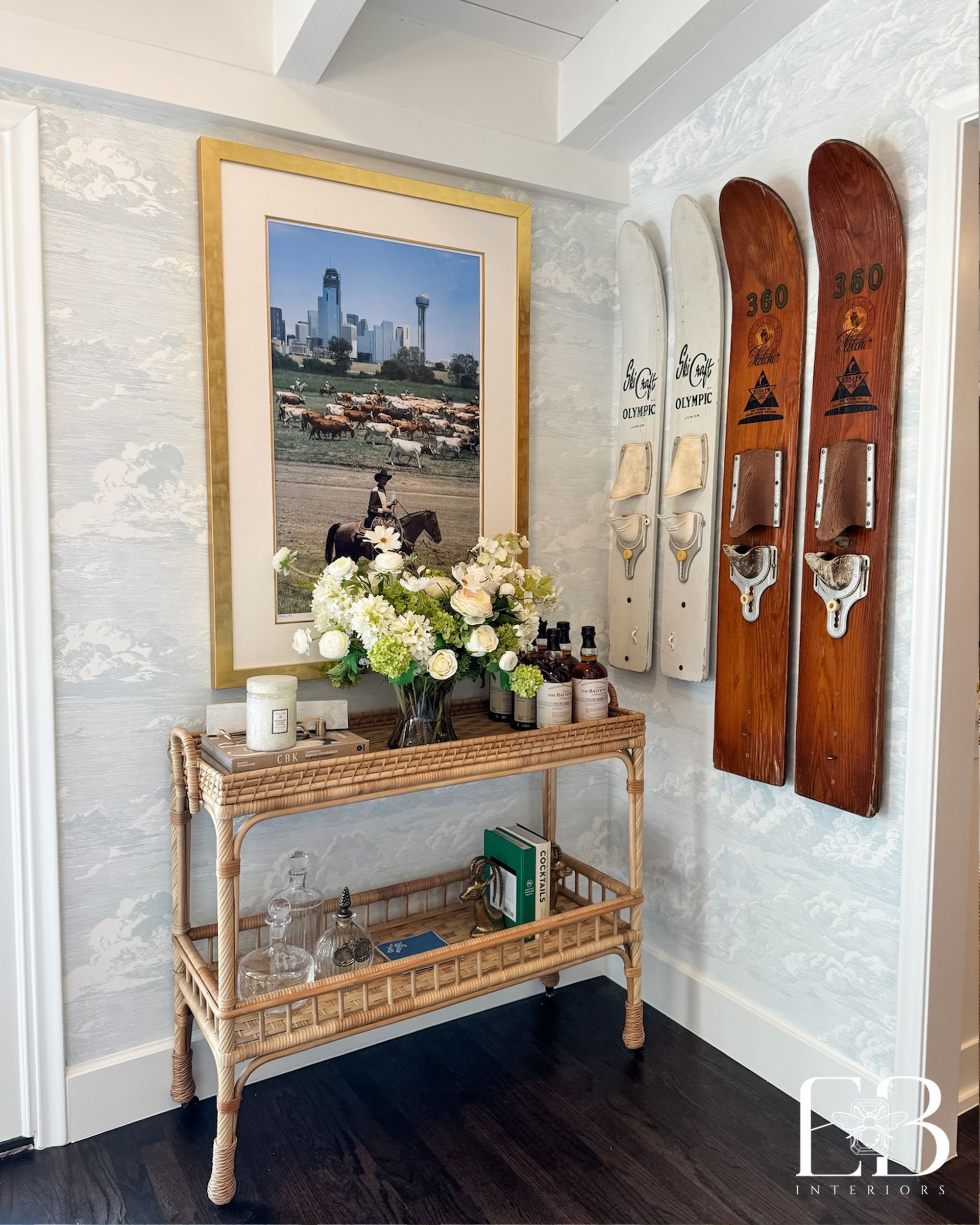 Bar cart vignette by Emerald Bee Interiors with vintage skis, floral accents, and Dallas skyline art framed in gold.