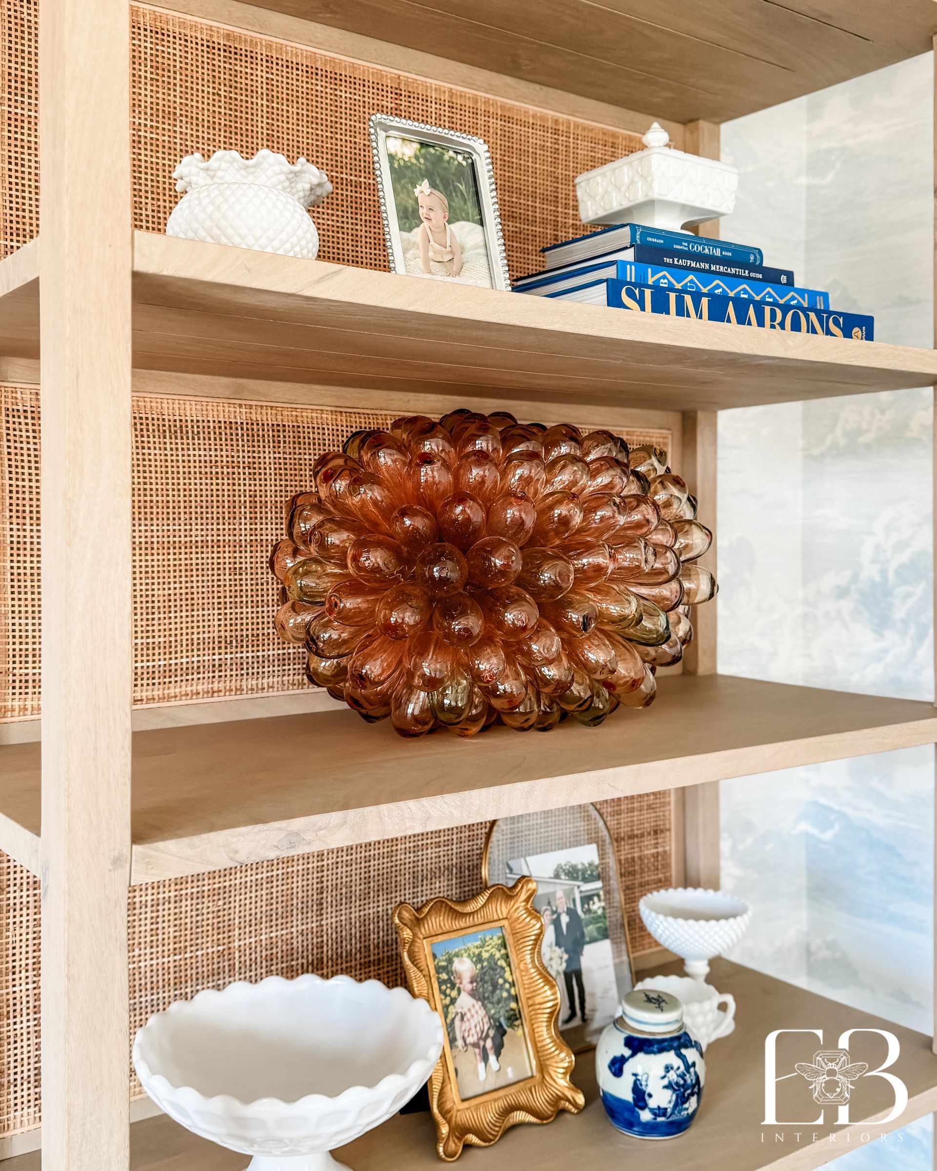 Bookshelf styled by Emerald Bee Interiors with vintage glass decor and family photos, adding texture and personality.