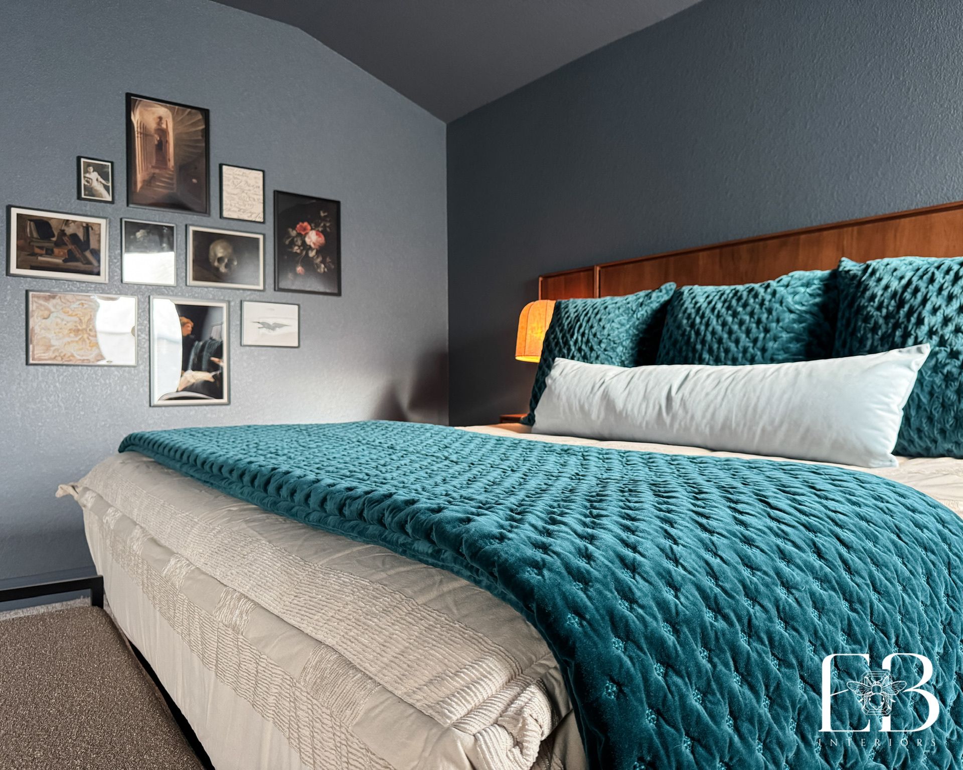 Dark blue bedroom by Emerald Bee Interiors with walnut headboard, teal velvet bedding, and an artful gallery wall.
