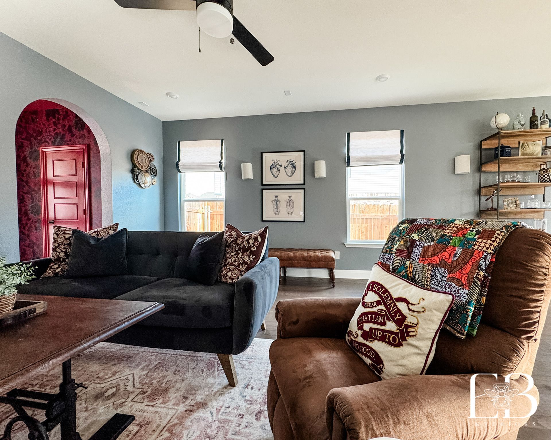 Living space by Emerald Bee Interiors with velvet sofa, red arched doorway, and curated art for bold yet cozy style.