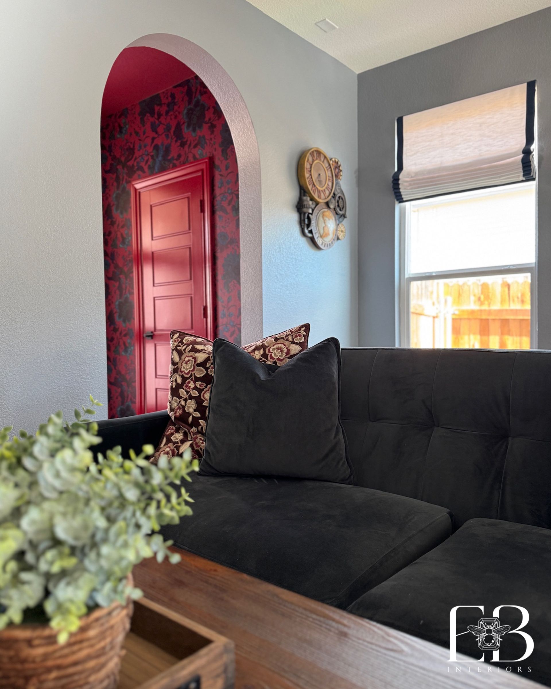 Detail of navy velvet sofa and red floral hallway arch in St. Cindy’s Way living room by Emerald Bee Interiors.