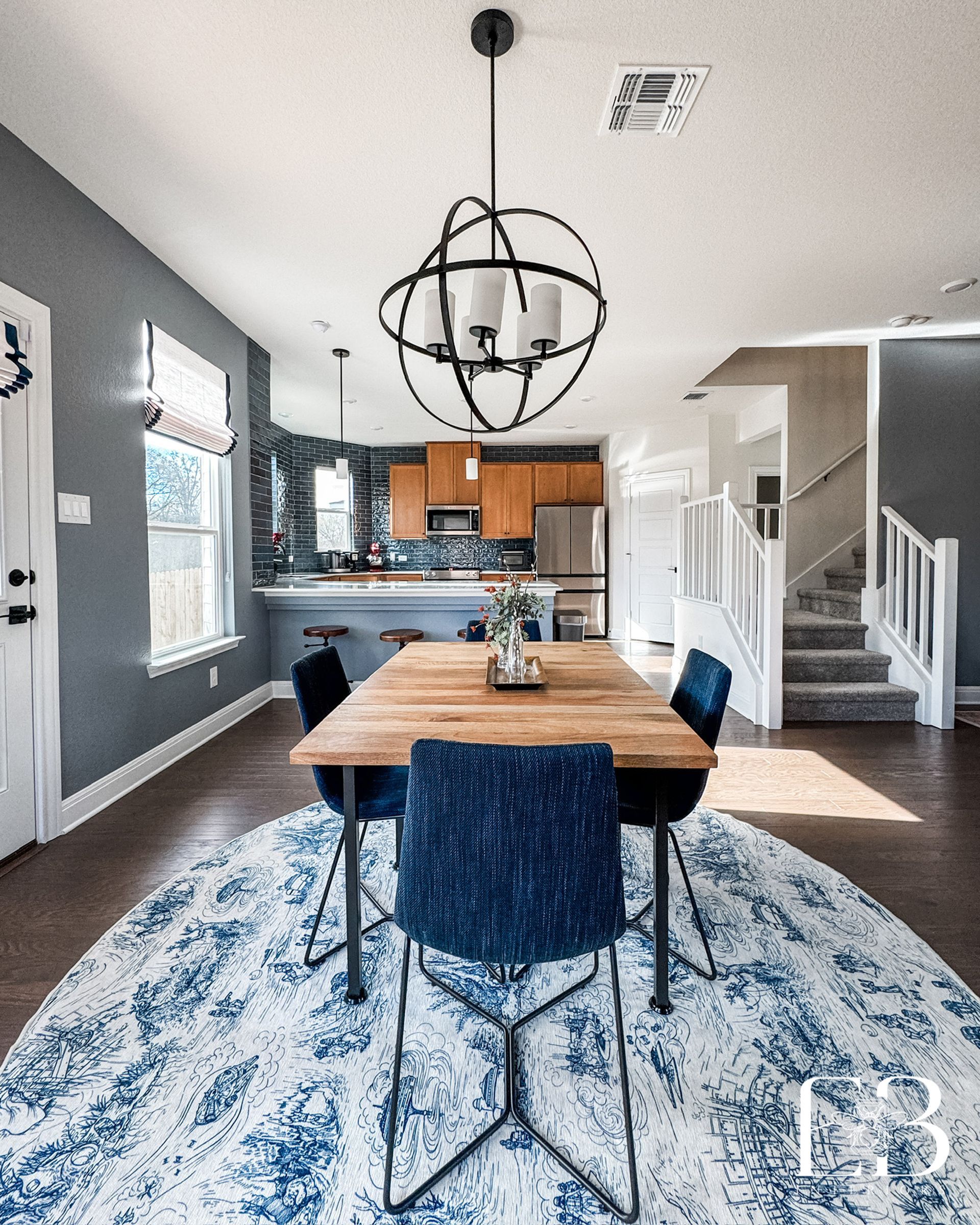 Open-plan living area with navy and red accents connecting to the kitchen and dining—designed by Emerald Bee Interiors.