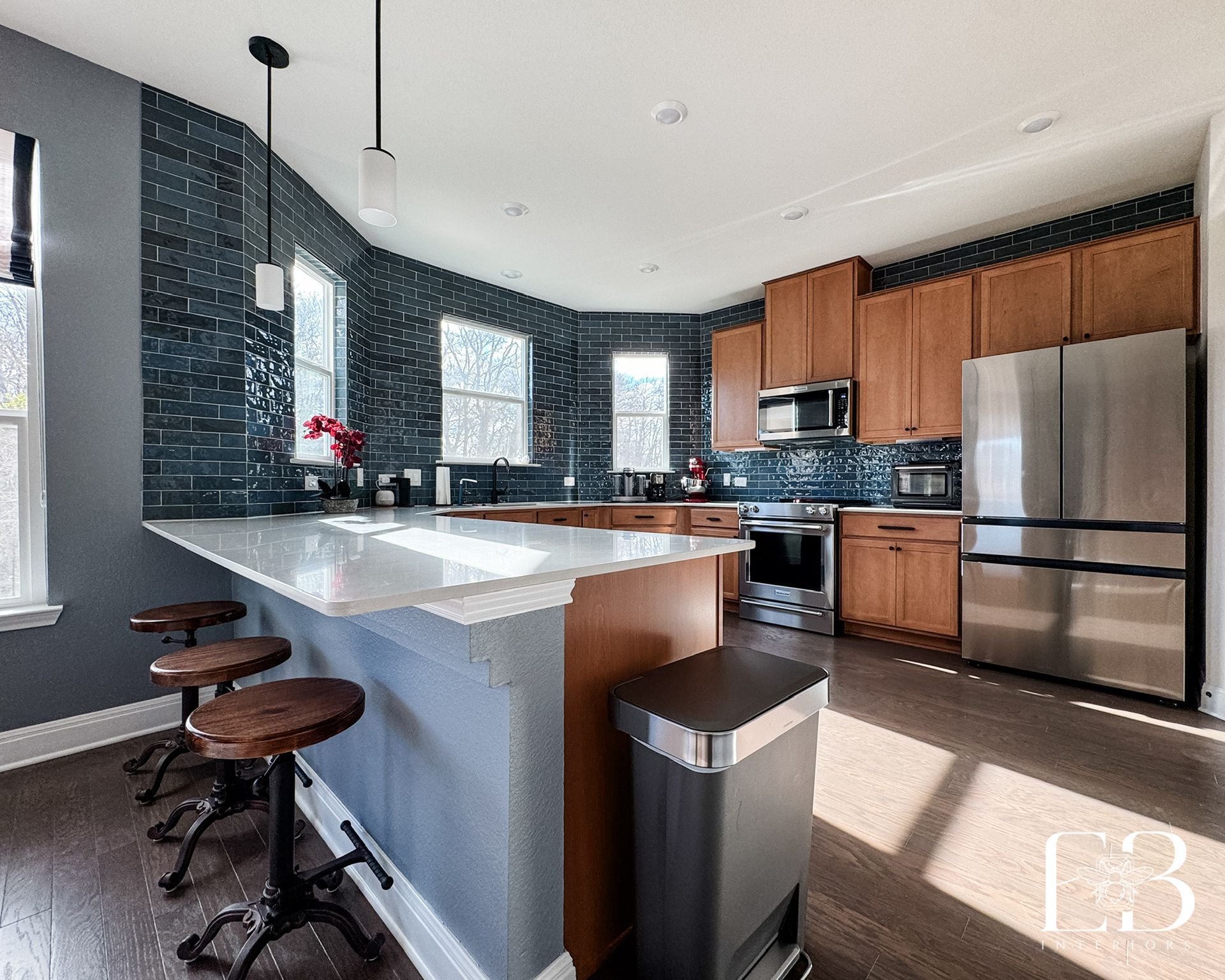 Kitchen detail with quartz countertops and potted orchid against blue subway tile, styled by Emerald Bee Interiors.