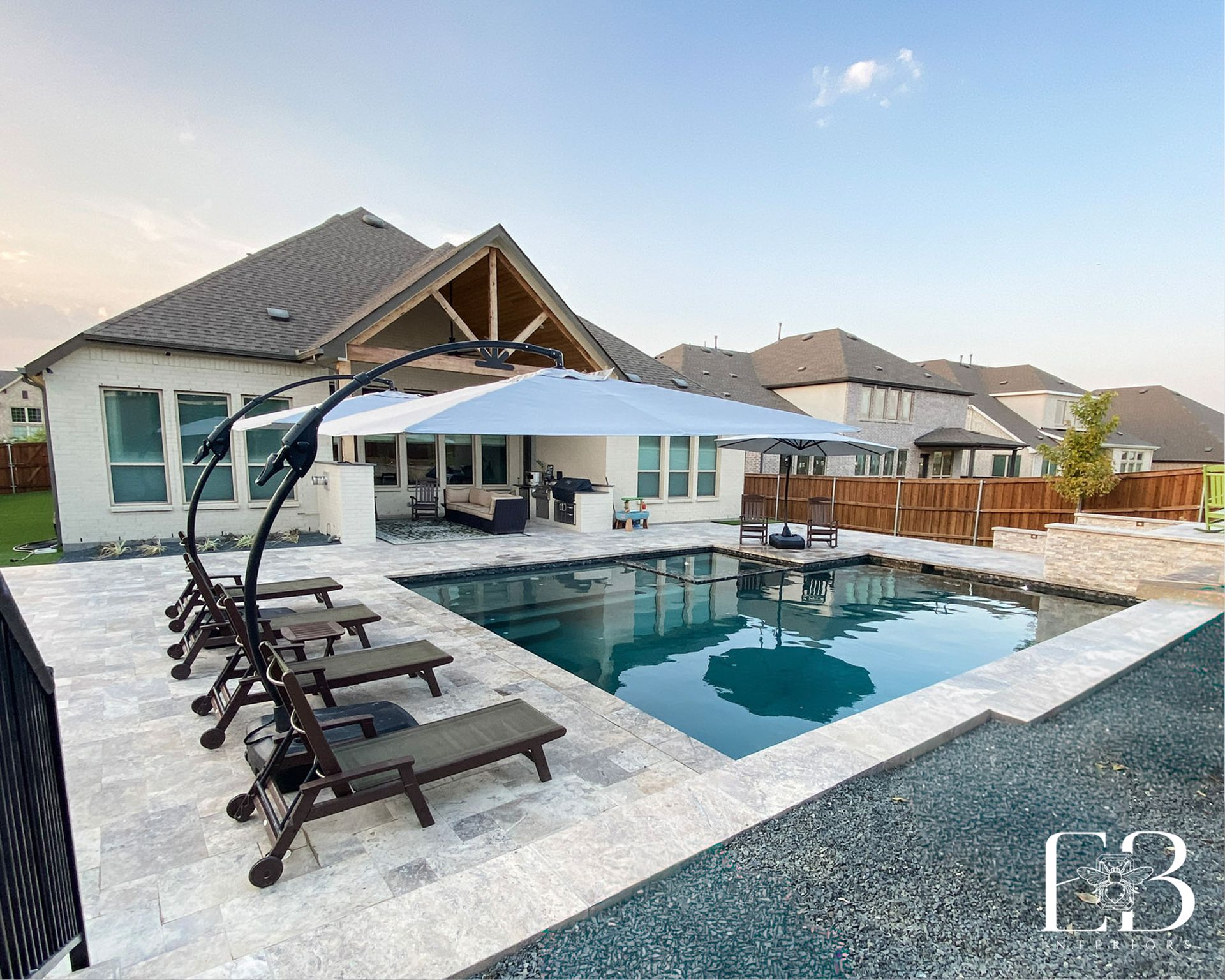 Backyard pool with lounge chairs, umbrella, and home.