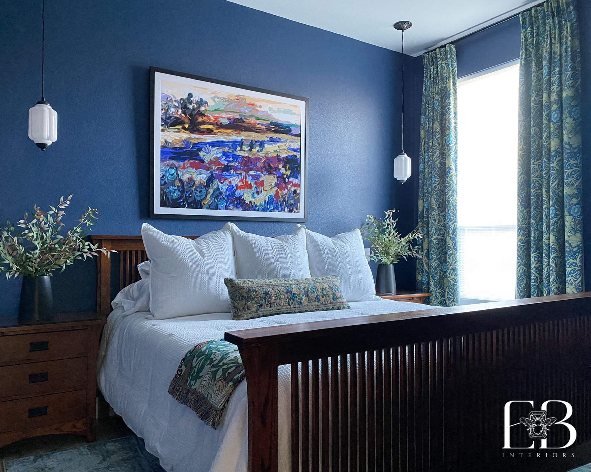 Bedroom with blue textured wall, art, bed, curtains, and two hanging lights.