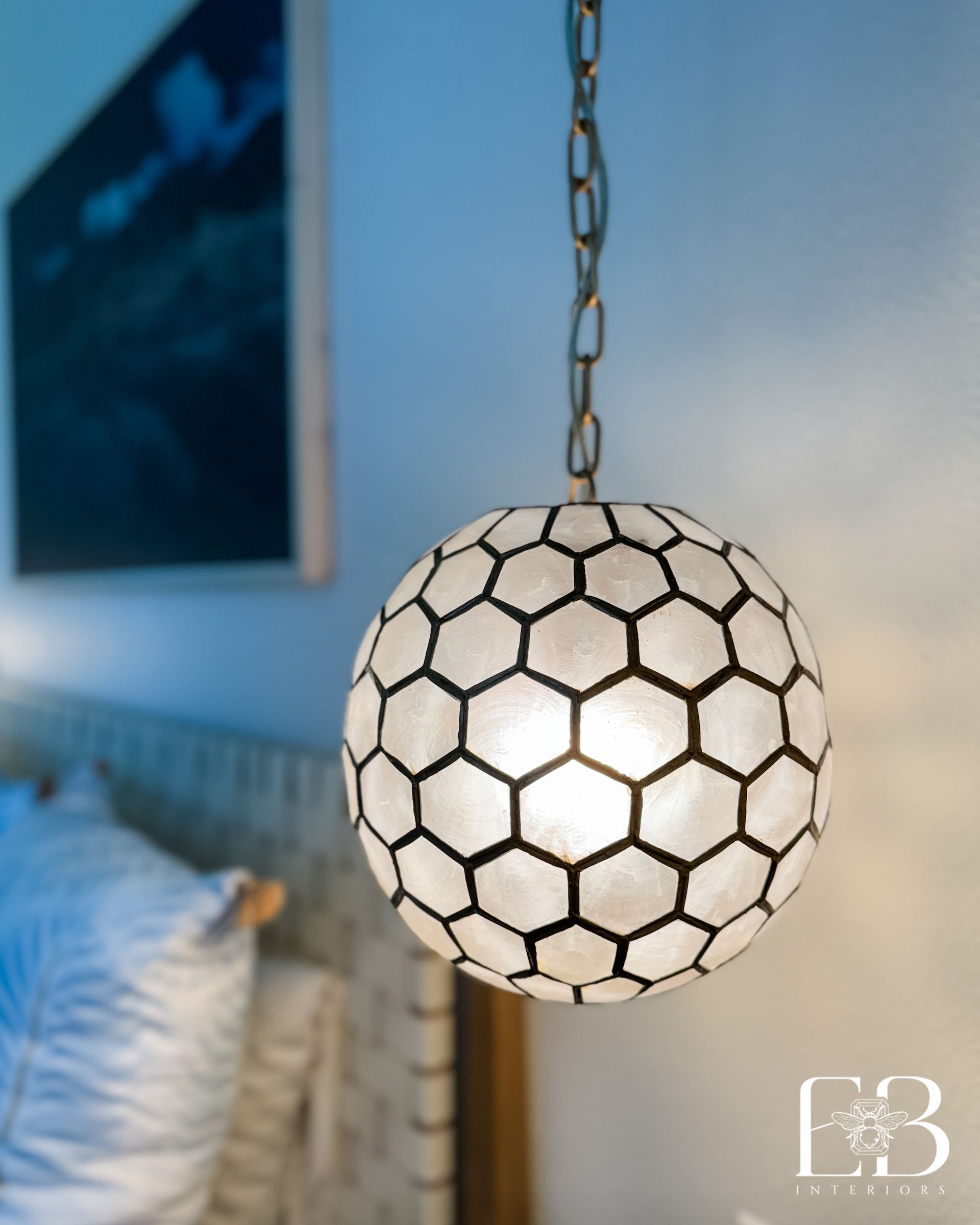 Pendant light with honeycomb shell design above bedside table in the Spanish Oak Trail suite by Emerald Bee Interiors.