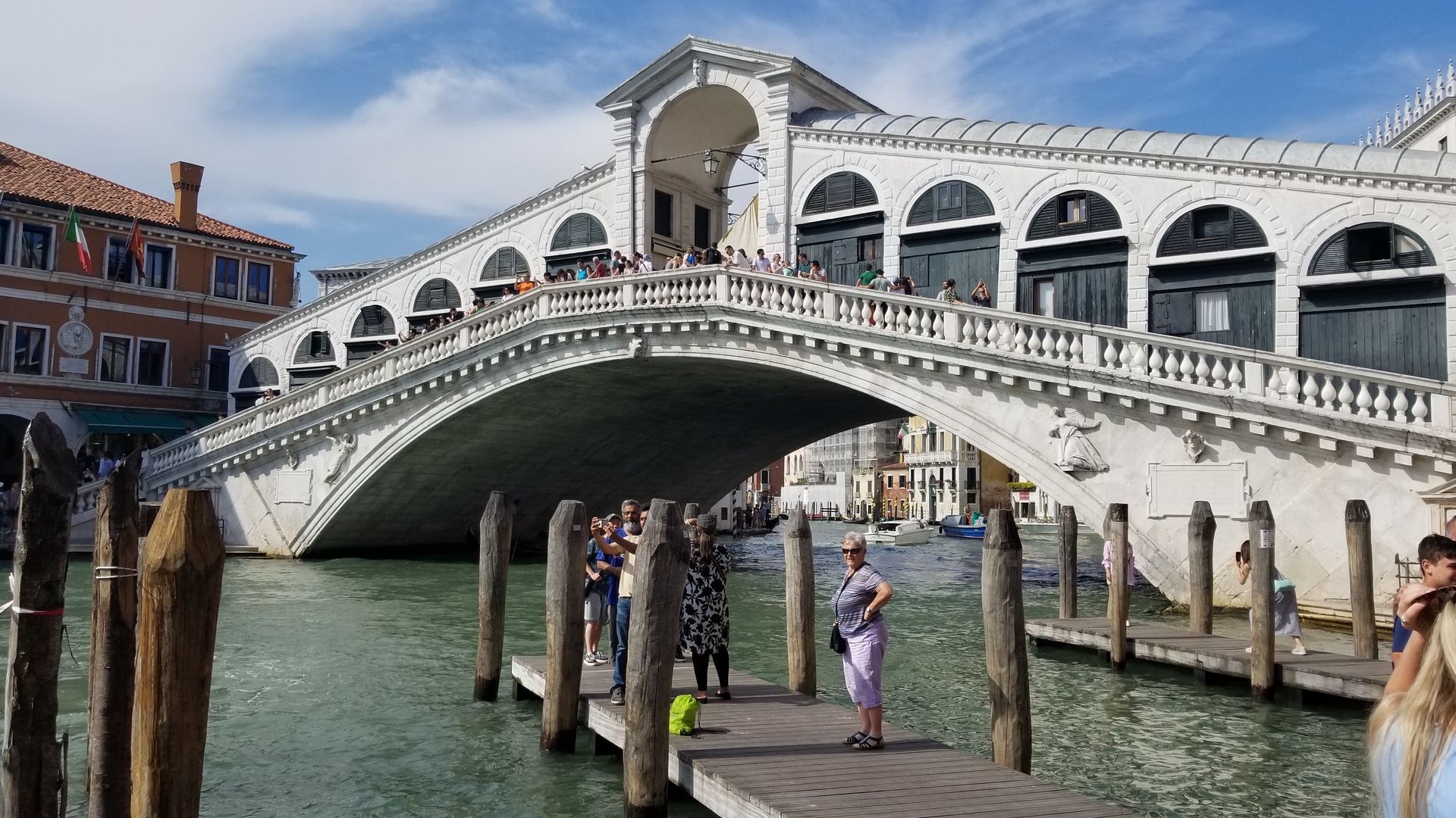 Venice Rialto Bridge over a canal, with pedestrians on the steps and market arcade buildings behind