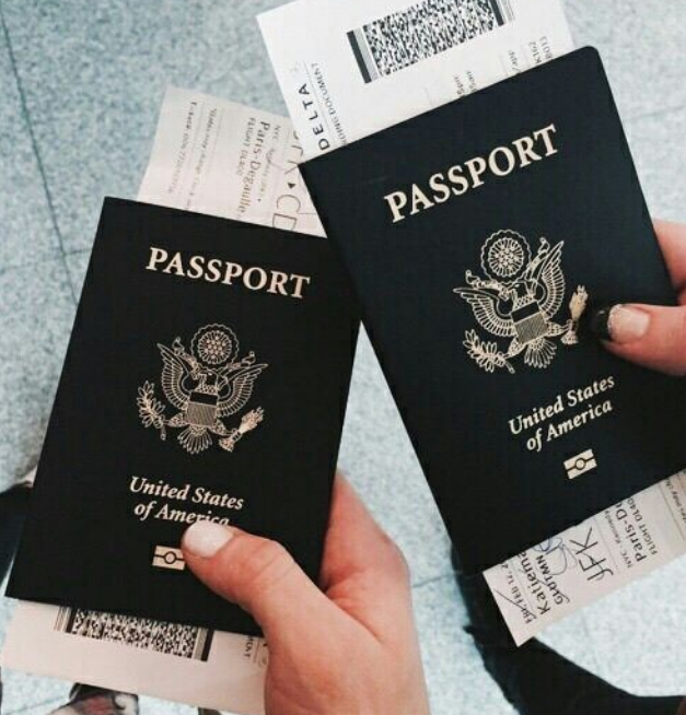 Two United States passports and boarding passes held by hands.