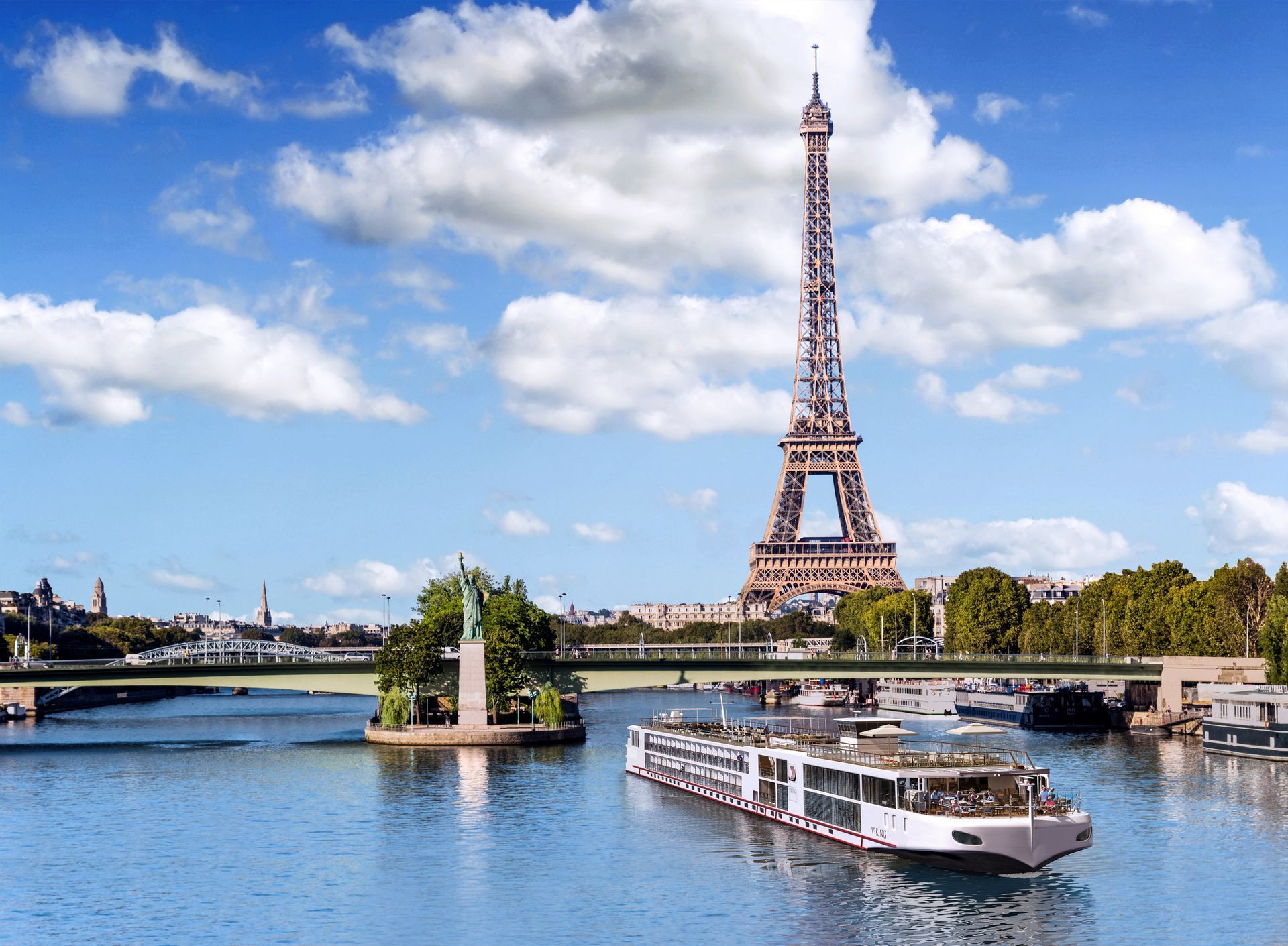 Eiffel Tower above the Seine in Paris, with a boat on the river under a partly cloudy sky