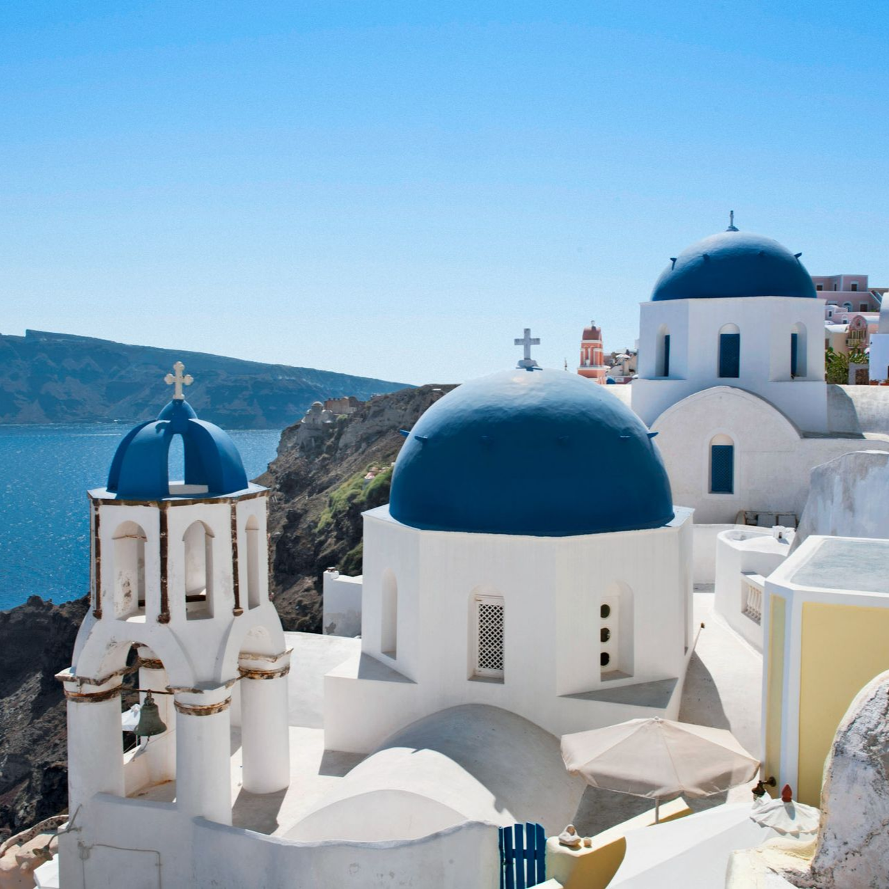 White and blue domed buildings on a cliffside overlooking the sea in Santorini, Greece