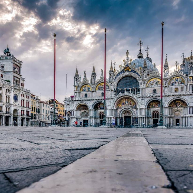 St. Mark’s Basilica and square in Venice at dusk, with ornate domes and a wide empty plaza.