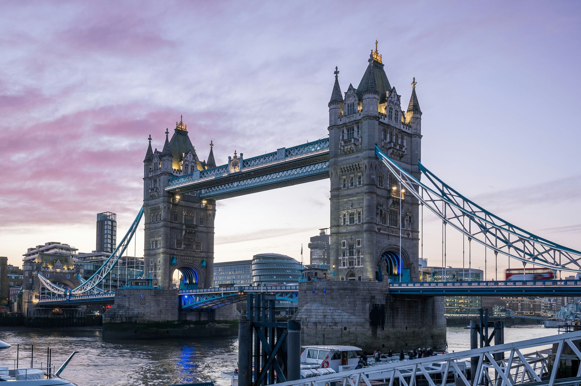 Tower Bridge over the River Thames at dusk, with a pink-blue sky and city lights reflecting on the water