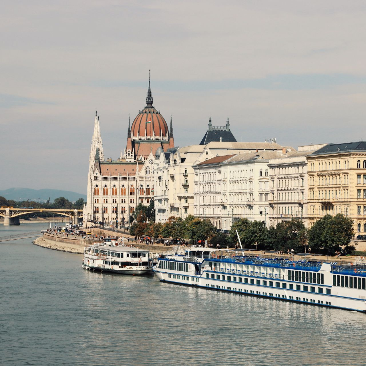 European riverfront cityscape with historic buildings, view from a river cruise with boats on the water