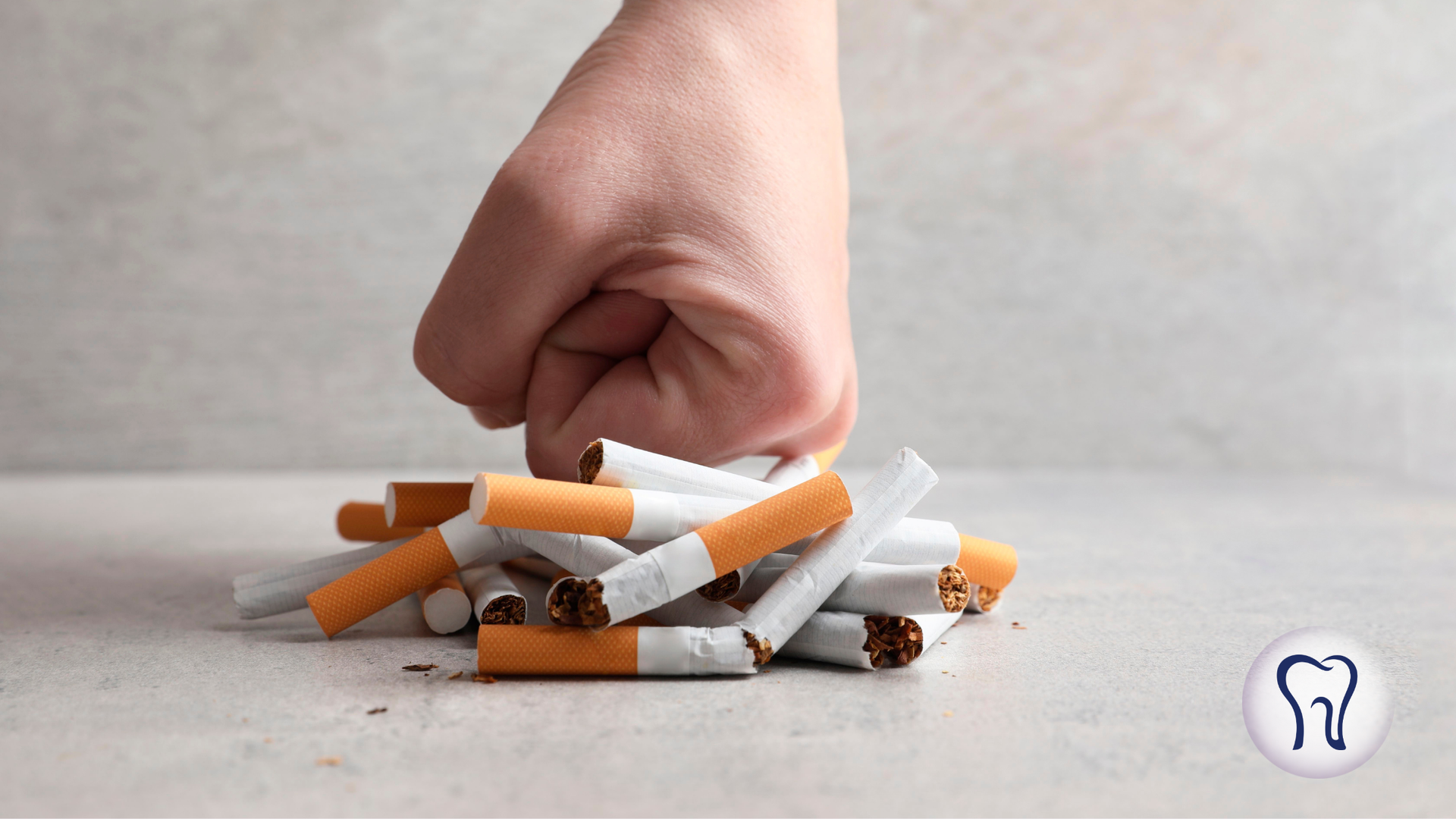 Fist smashing cigarettes on a gray surface, symbolizing quitting smoking.