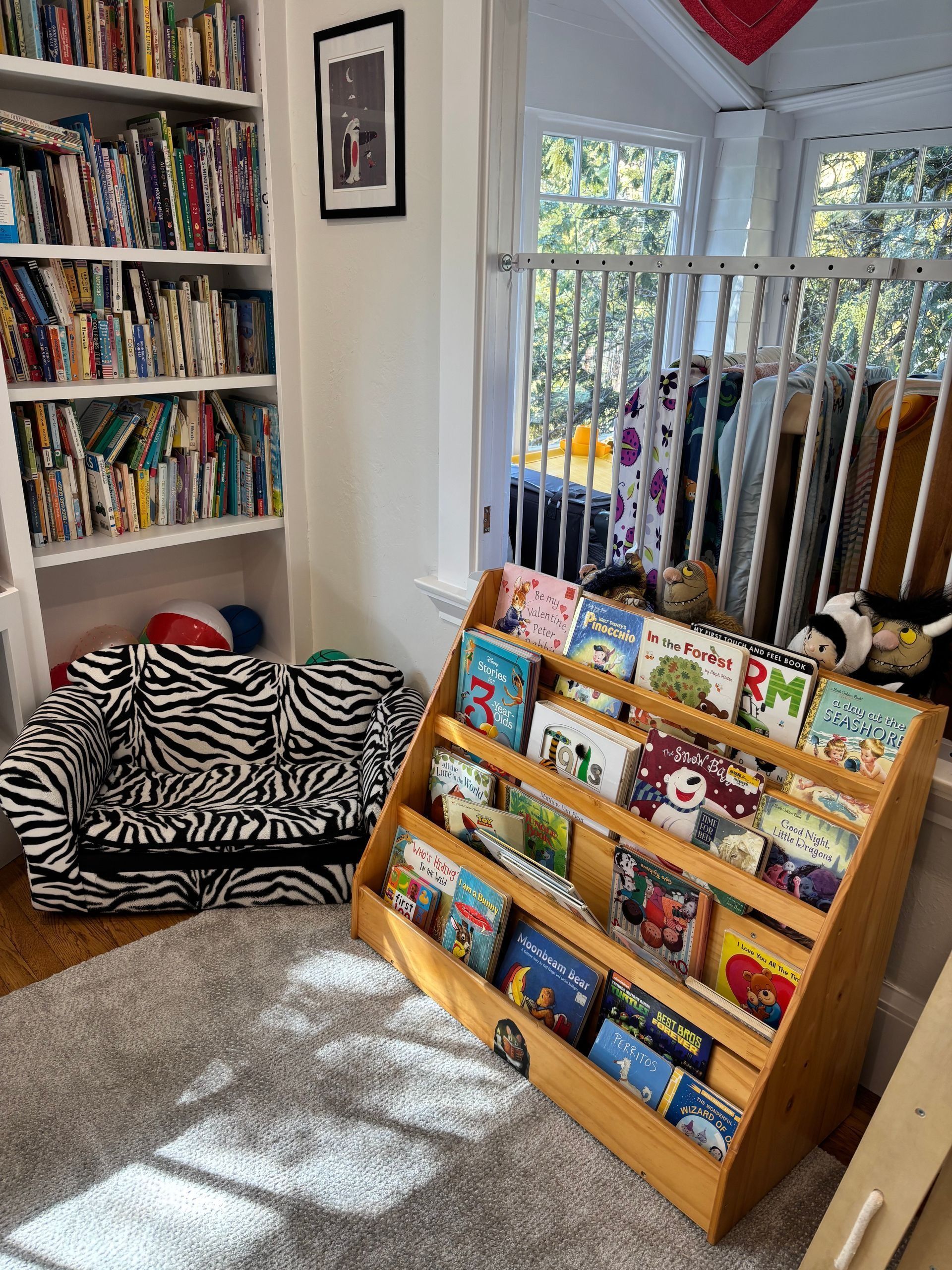 Children’s book display in a cozy room with zebra-print floor cushions and sunlight by a window