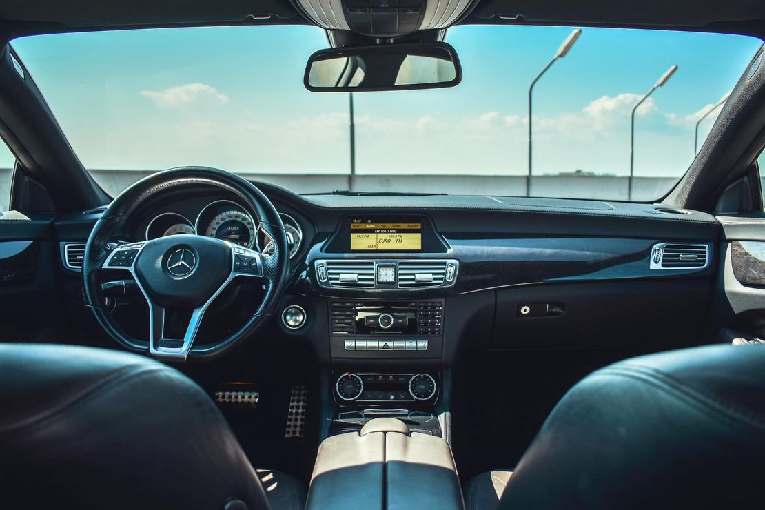 The interior of a car with a steering wheel and a rear view mirror.