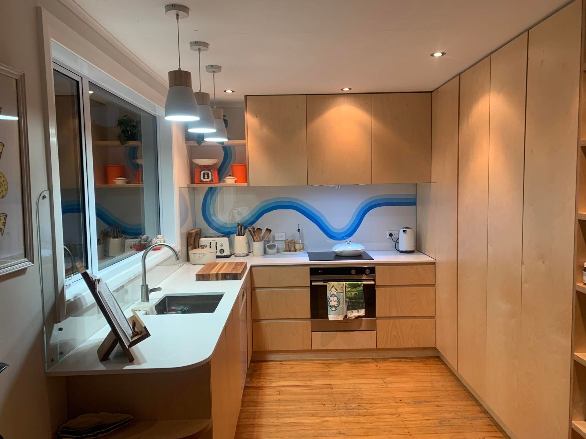 A kitchen with wooden cabinets , a sink , a stove , and a window.