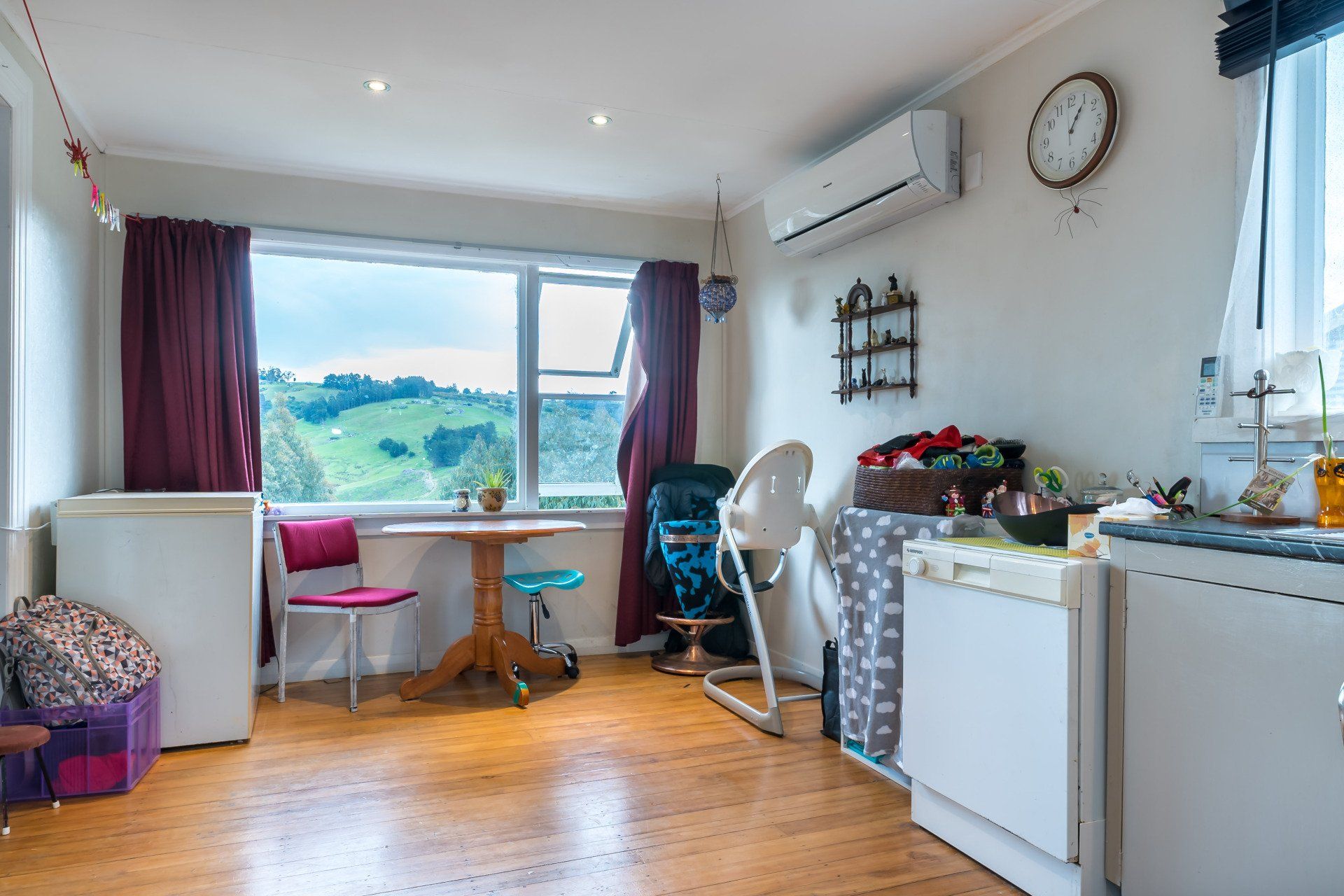 A living room with a table , chairs , and a clock on the wall.