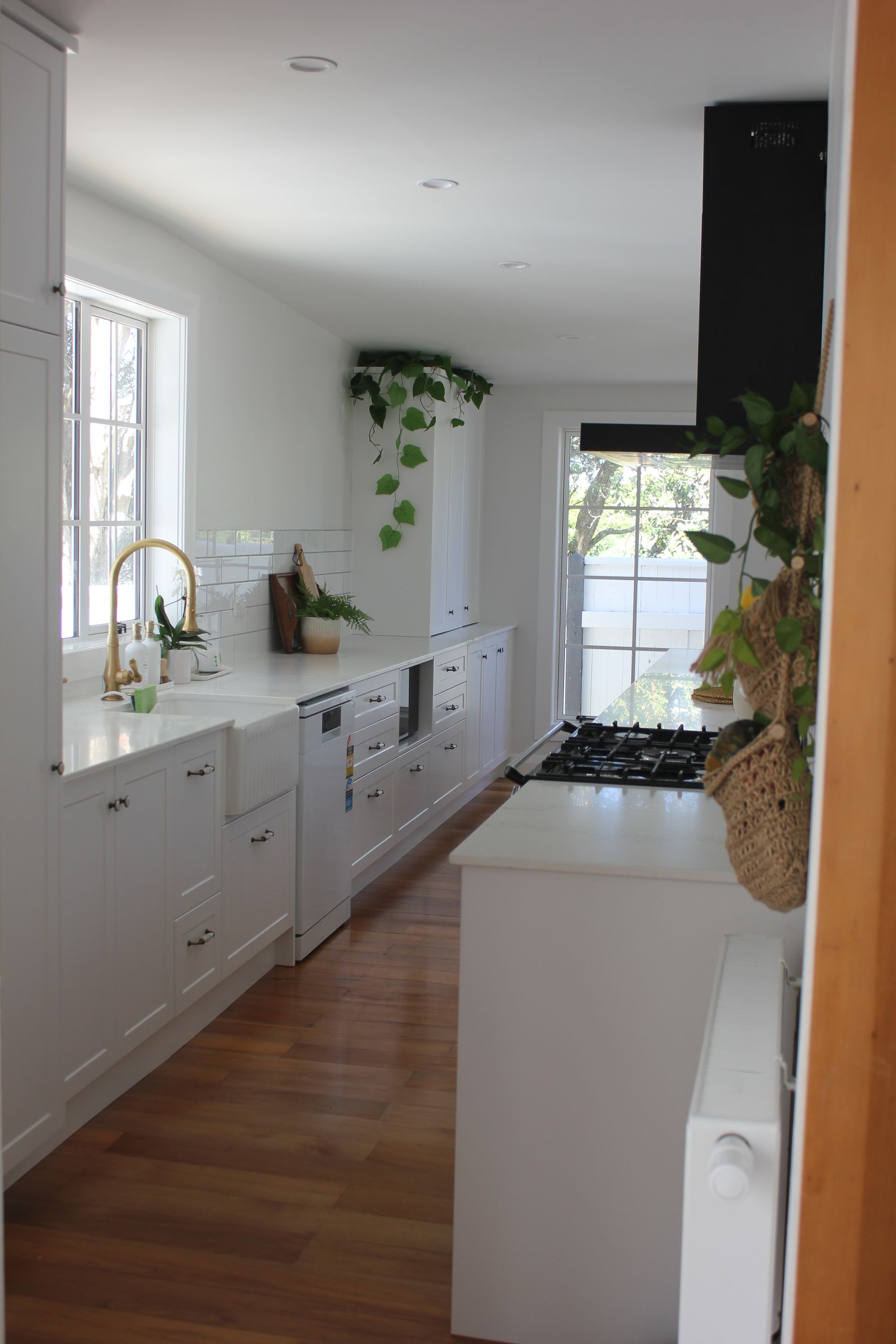 A kitchen with white cabinets , a sink , a stove , and a window.