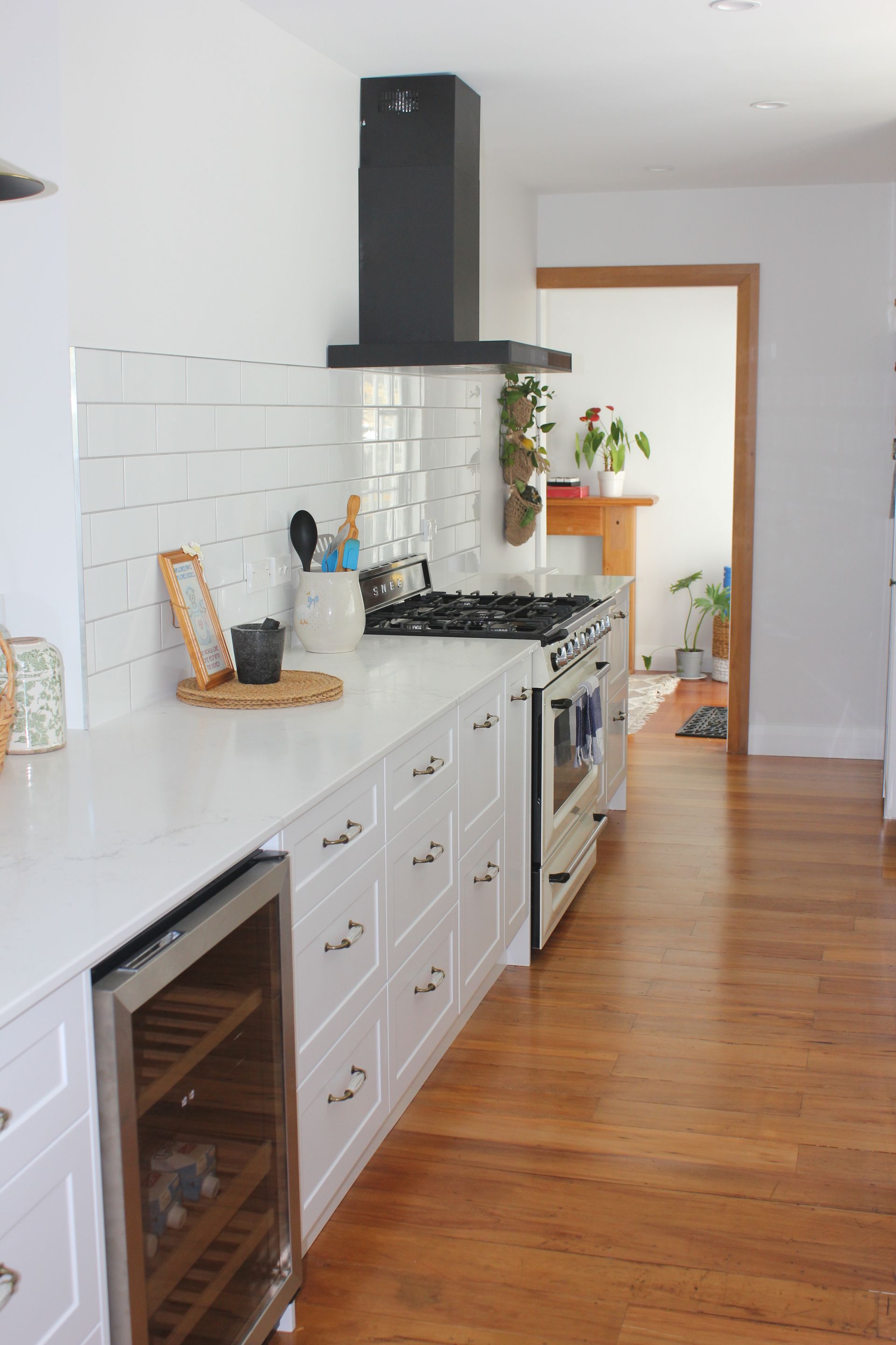 A kitchen with white cabinets , a stove , a refrigerator and a wine cooler.