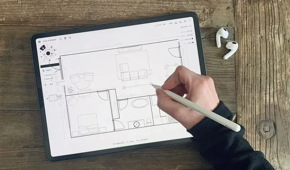 A person is drawing a floor plan on a tablet with a pencil.