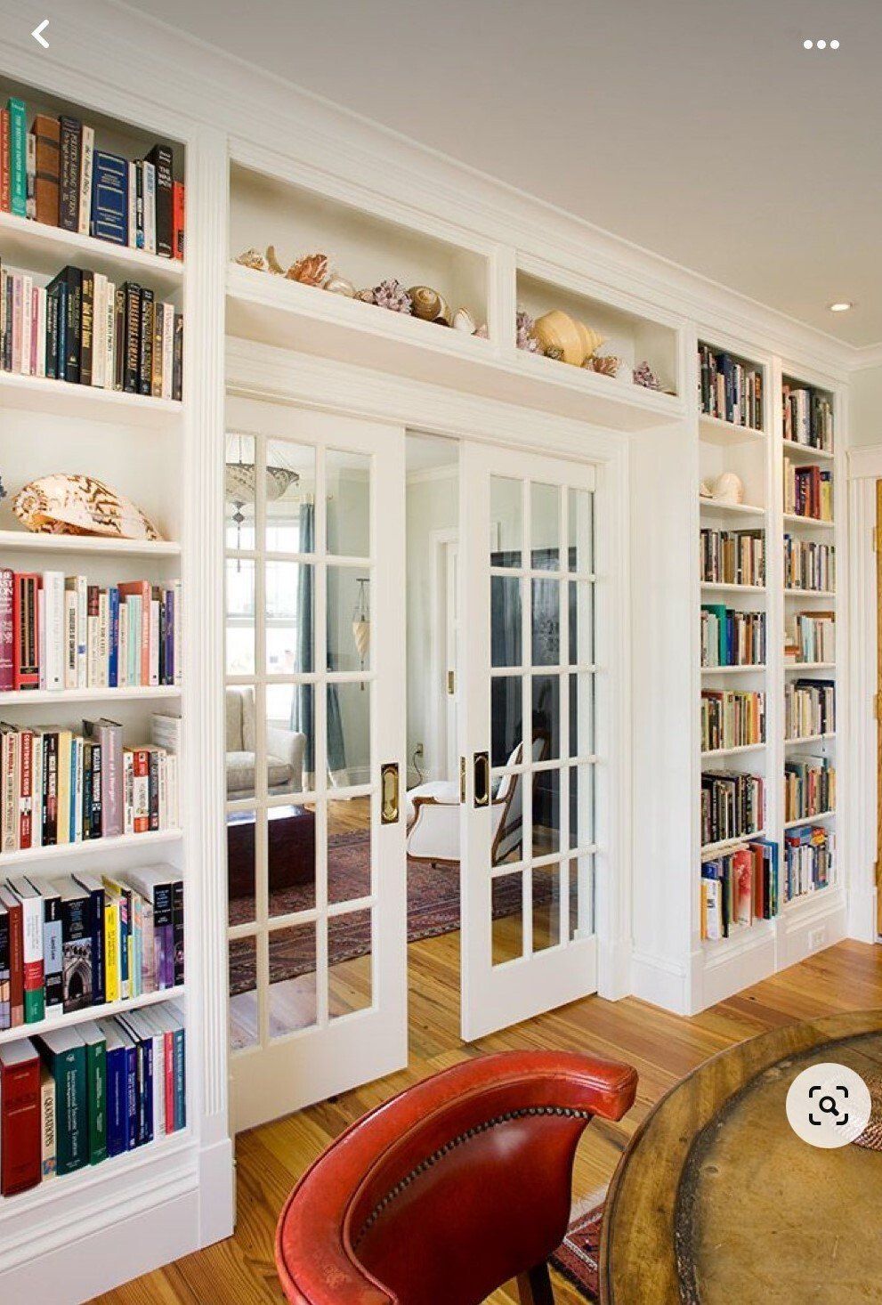 A living room with lots of bookshelves and french doors