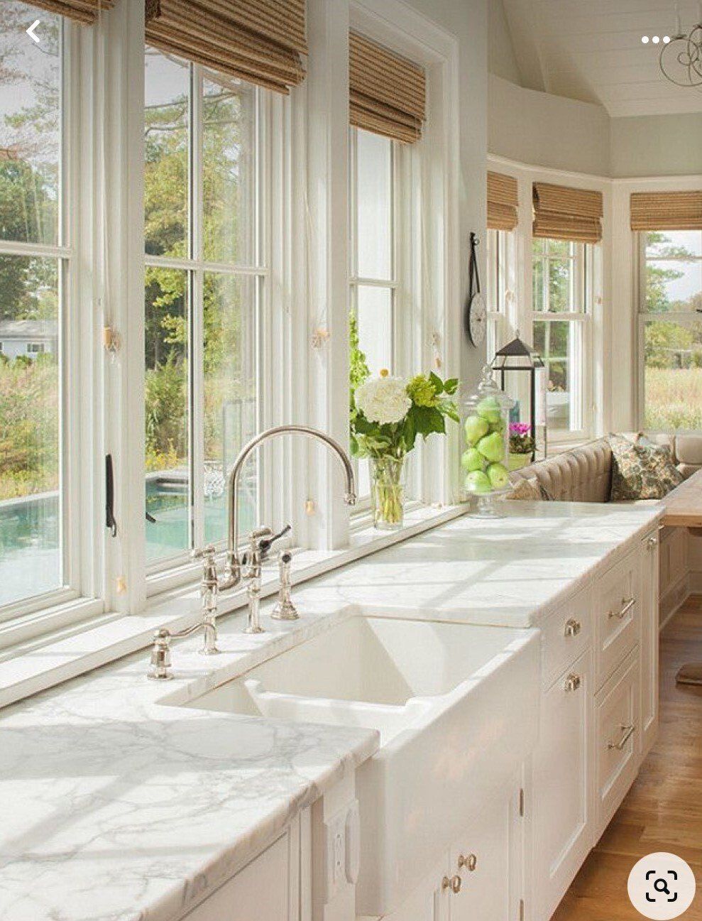 A kitchen with two sinks , a faucet , and a lot of windows.