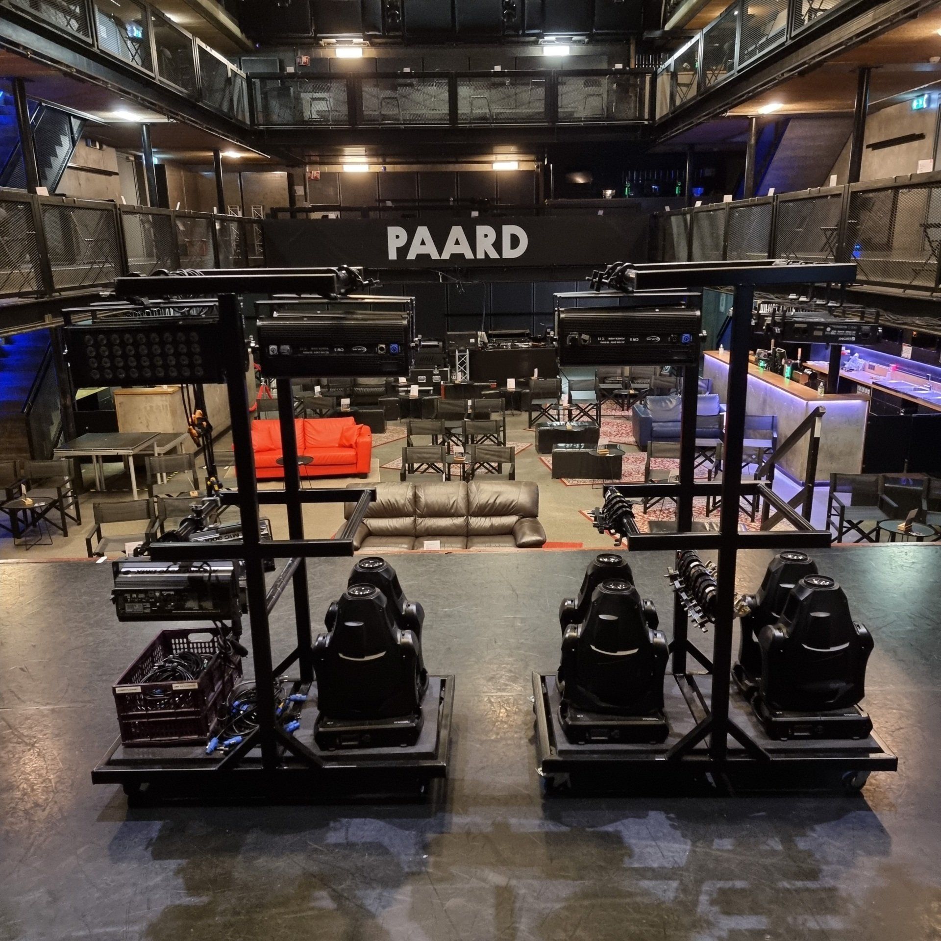 Twee verrijdbare stands met zwarte racestoelen en projectoren op een podium met uitzicht op de zaalvloer van PAARD.