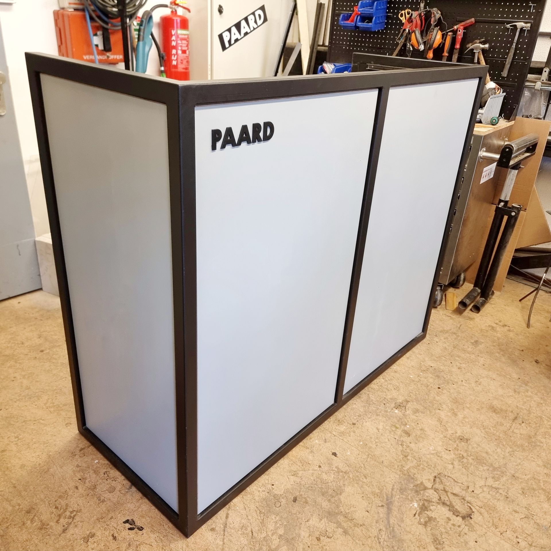 Een draagbare DJ-booth met een zwart frame en lichtgrijze panelen, voorzien van het zwarte 