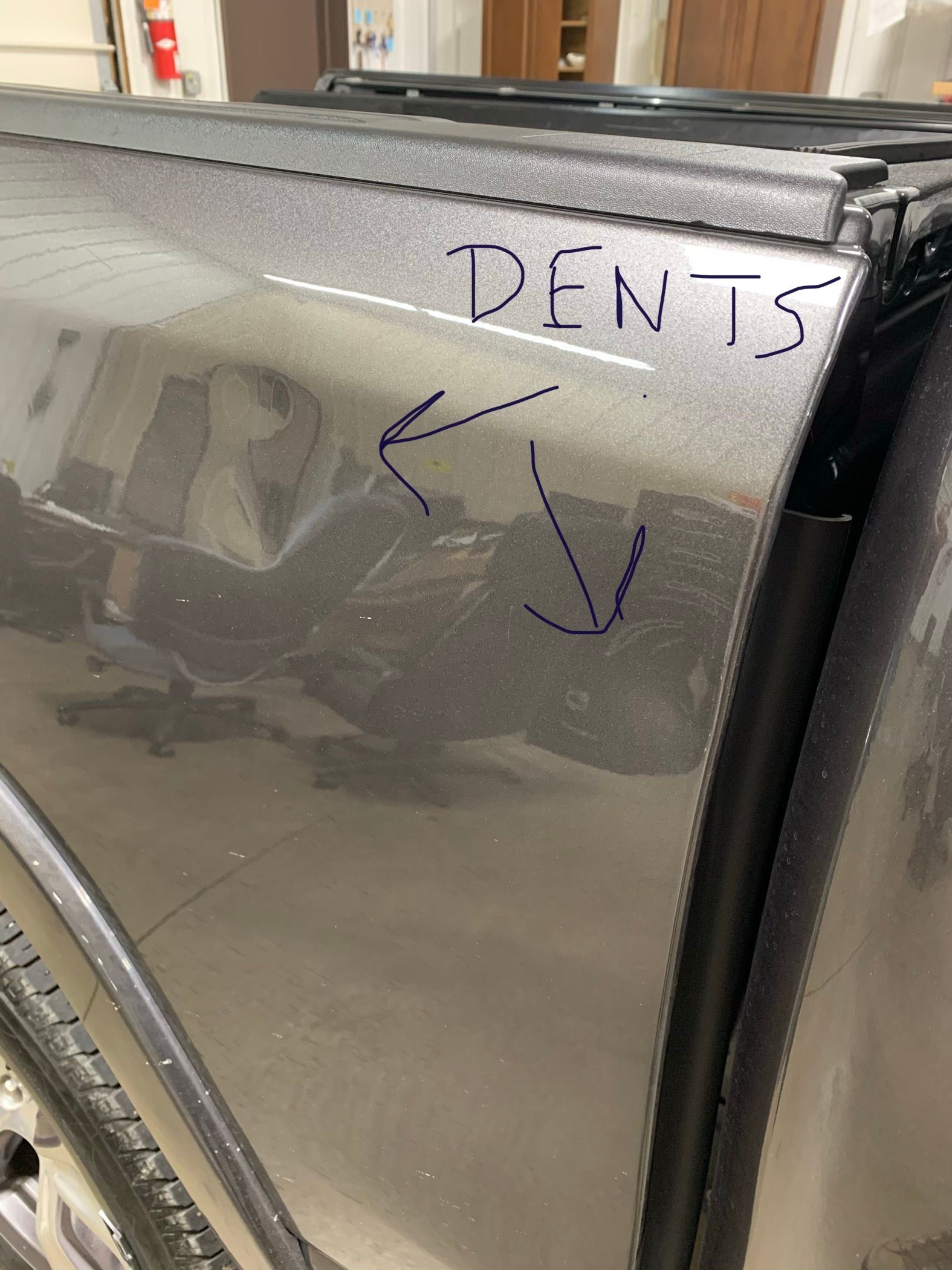 Close-up of a silver car door with visible dents and marker arrows pointing to damage