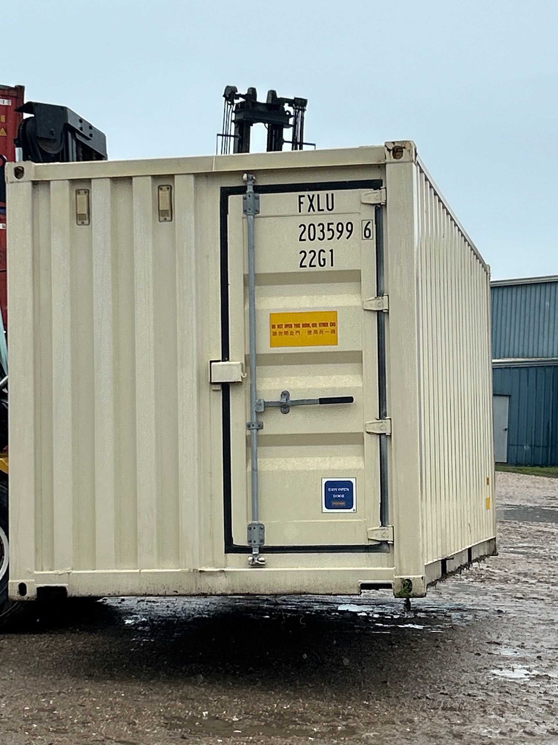 Green shipping container door with vertical metal bars and a black handle.