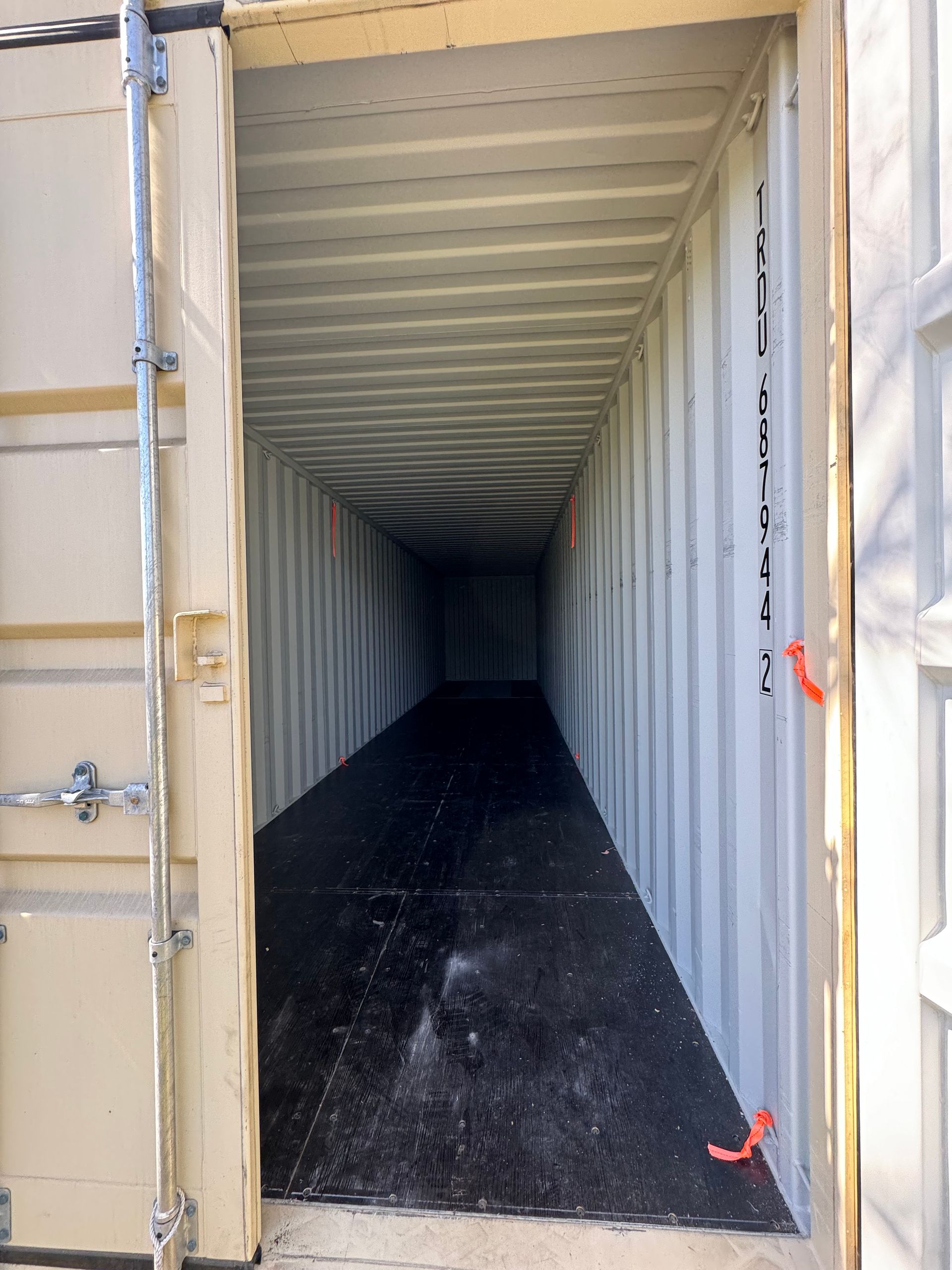 Open shipping container with dark floor and empty interior, viewed from the entrance.