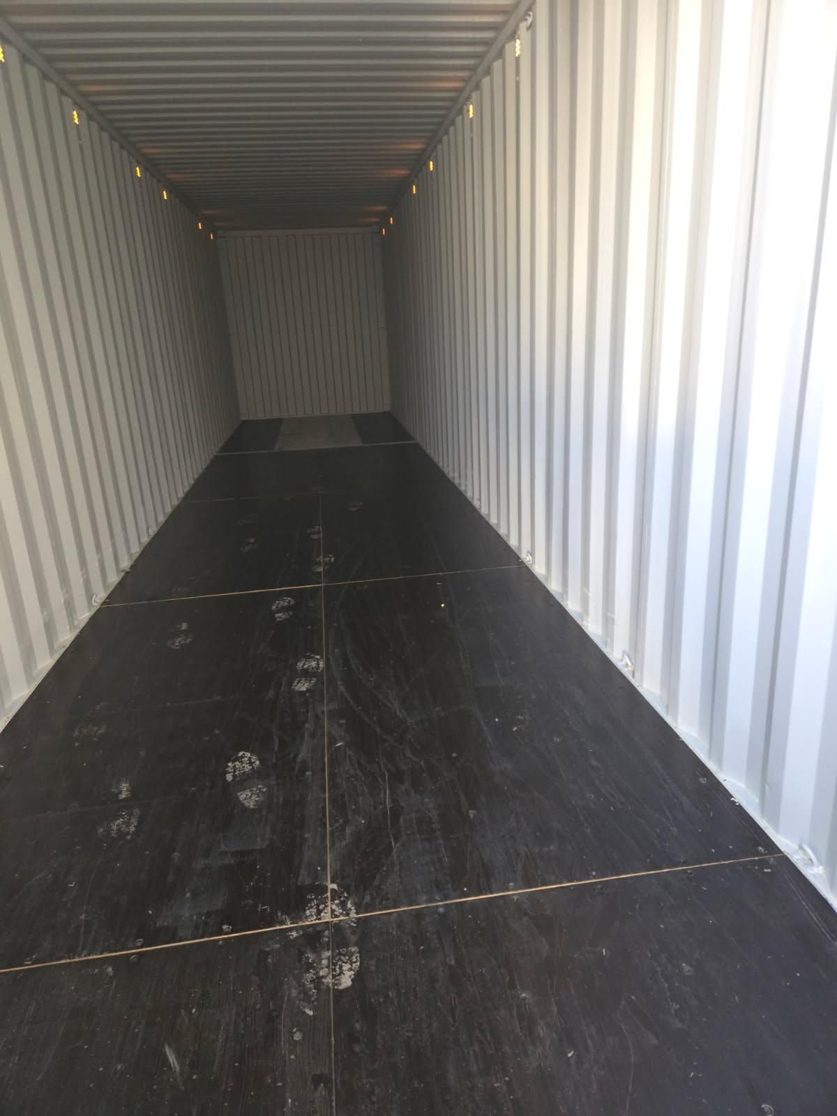 Empty shipping container interior with corrugated metal walls and a dark floor