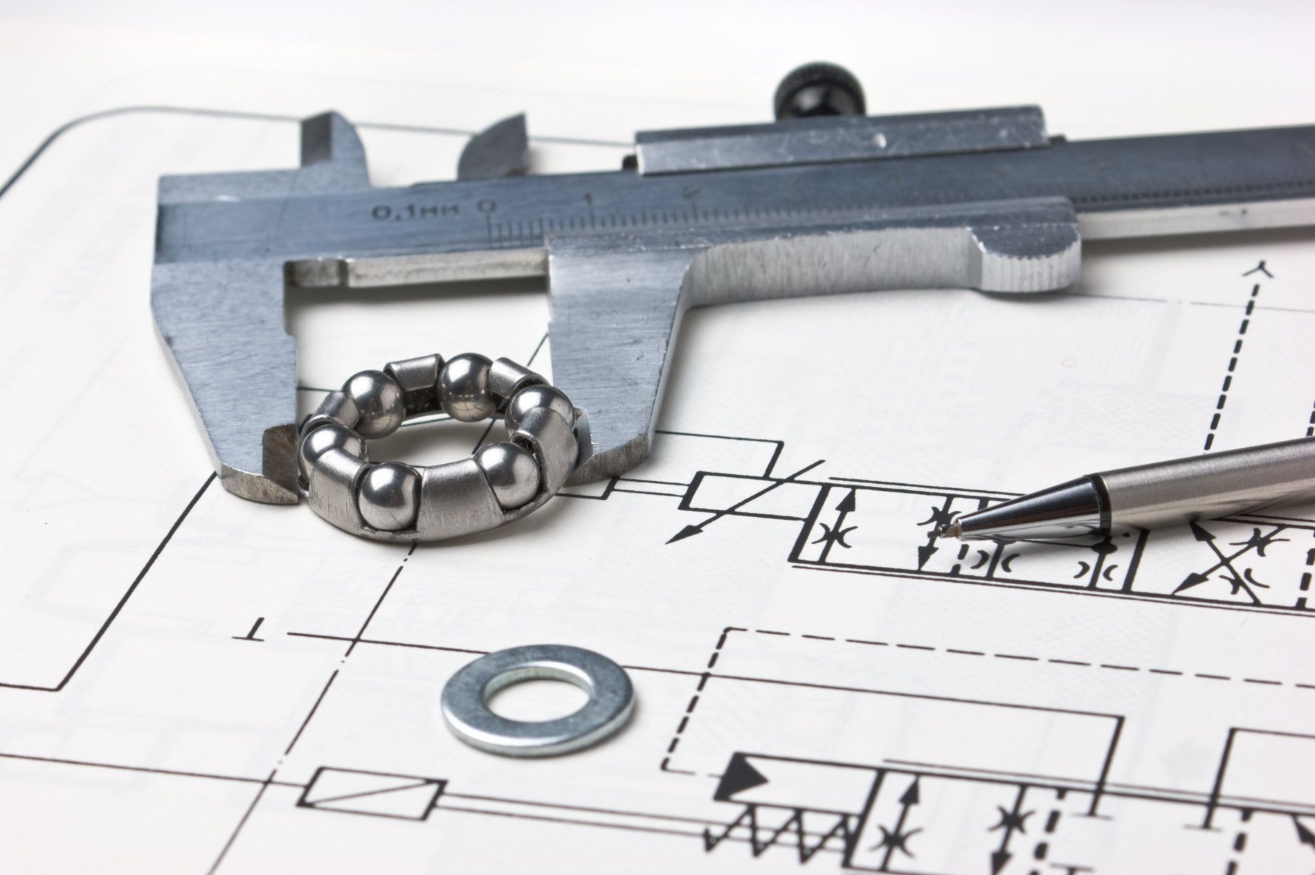 A ball bearing being measured with calipers on a blueprint, with a pen and a washer — Darren Gray Cad Services In Upper Corindi, NSW