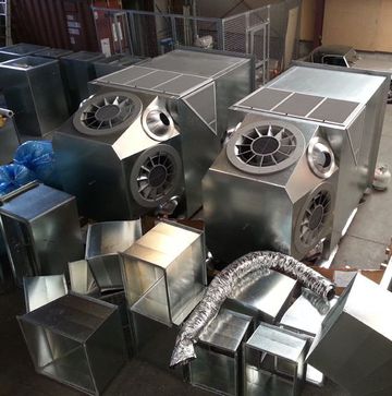 Metal ventilation units and ductwork components in a workshop setting.