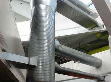 Ventilation ducts running through a building with white support beams.