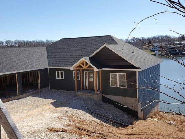 Damaged asphalt shingle roof with missing sections, outdoors with trees in the background.
