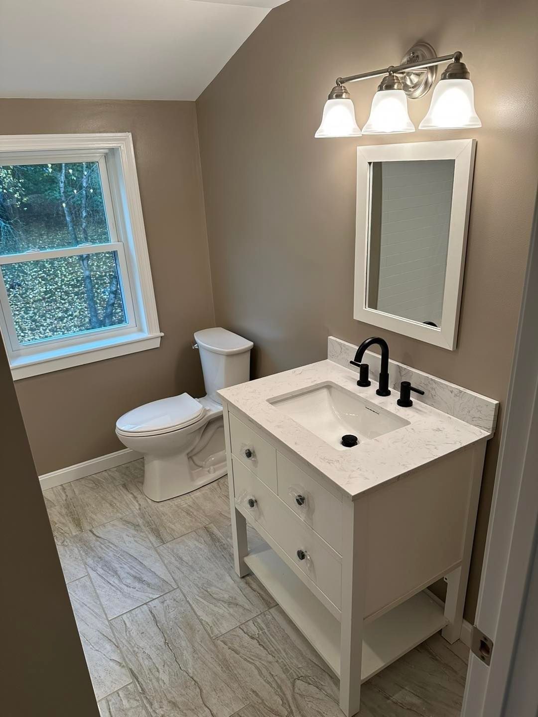 A bathroom with a sink , toilet and mirror.