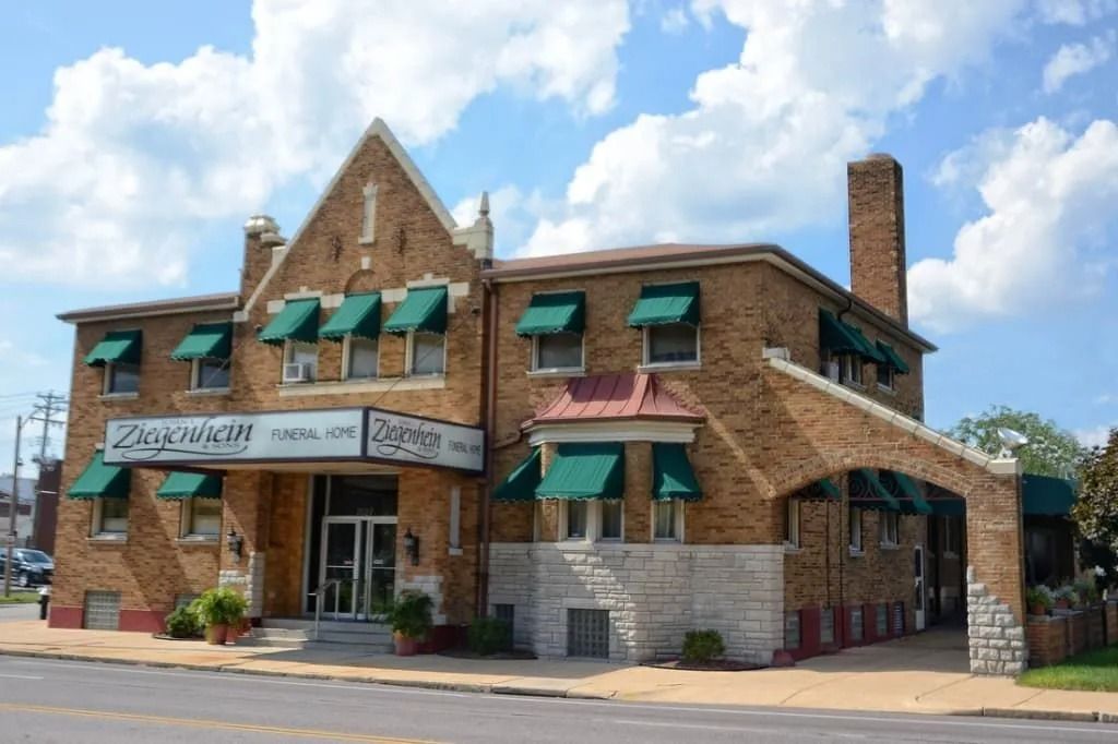 Brick building with green awnings and a white sign on a sunny street corner