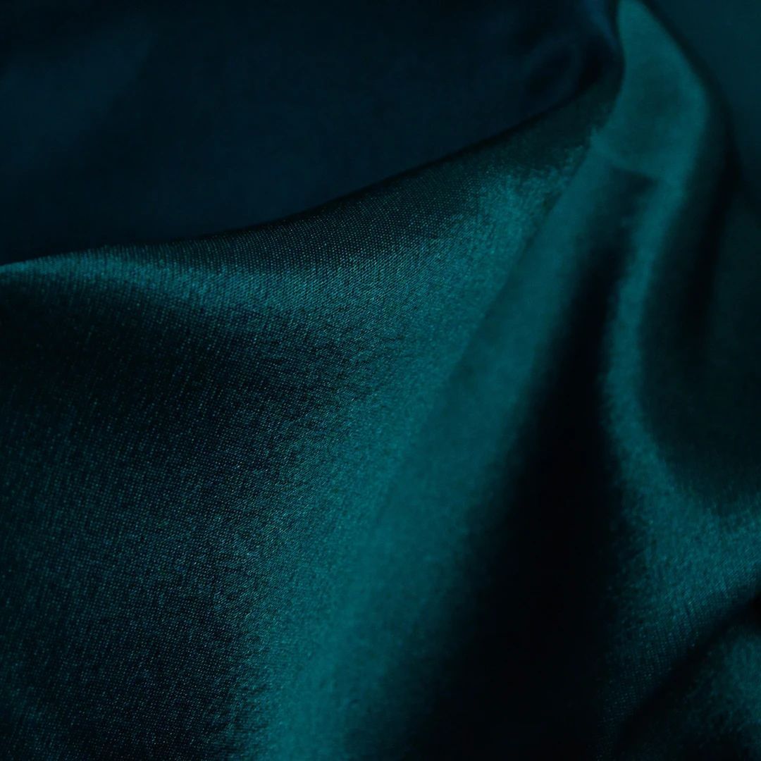 Close-up of dark teal textured fabric with soft folds and highlights