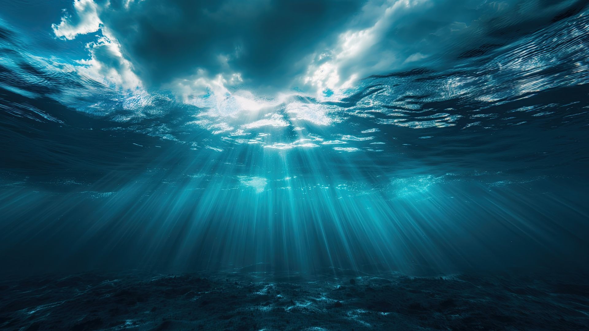 Sunbeams streaming through the surface of a blue ocean with dark seabed below