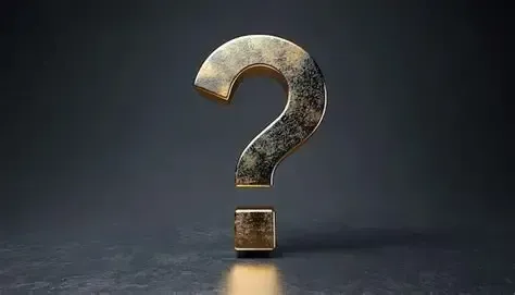A metallic question mark standing upright on a dark surface against a dark background.