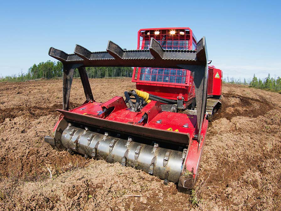 A red bulldozer is driving through a dirt field.